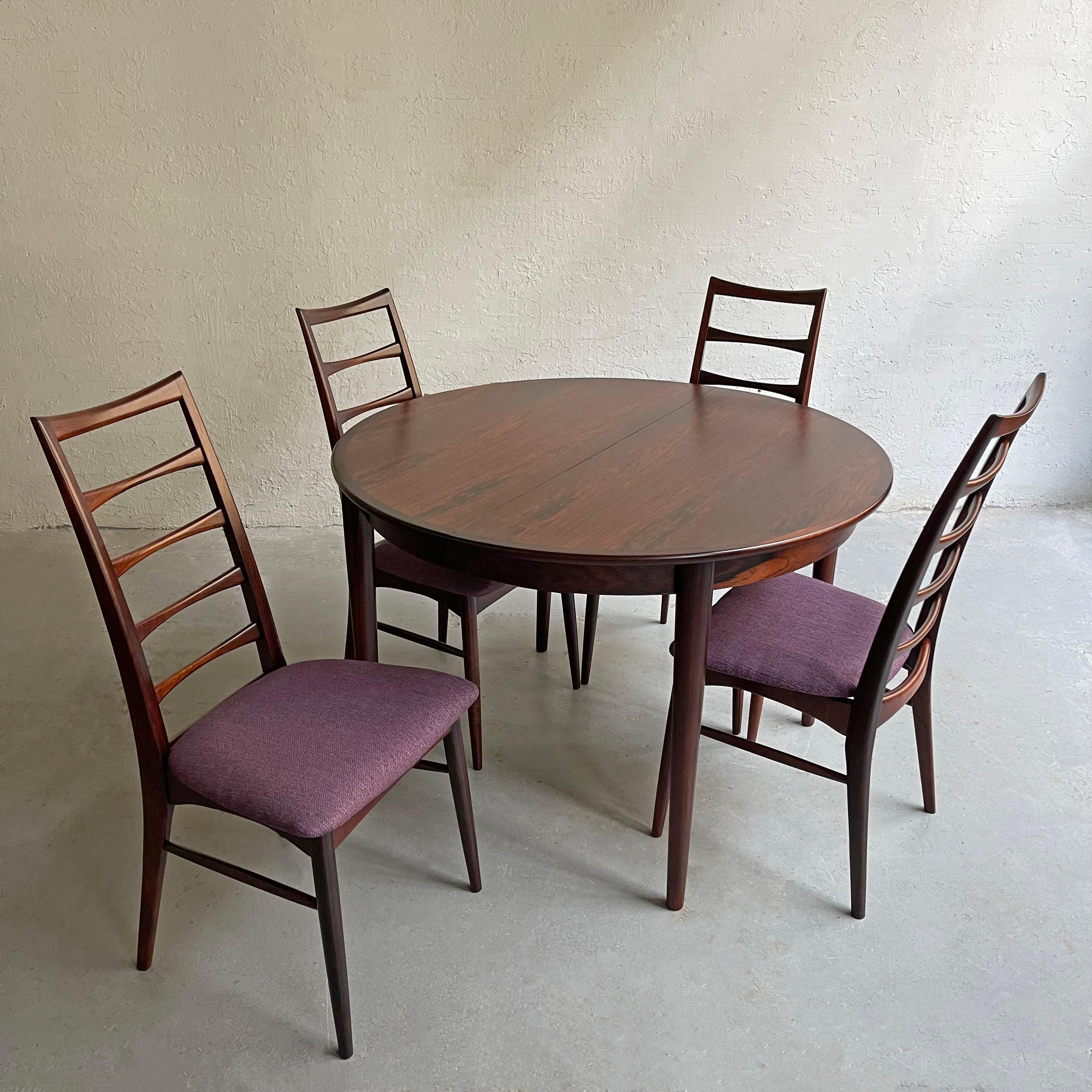Danish Modern, rosewood dining set by Niels Koefoed, Hornslet Møbelfabrik features a 43 inch round dining table that extends up to 83 inches with two 20 inch leaves and 4 elegant, high ladder back , model 