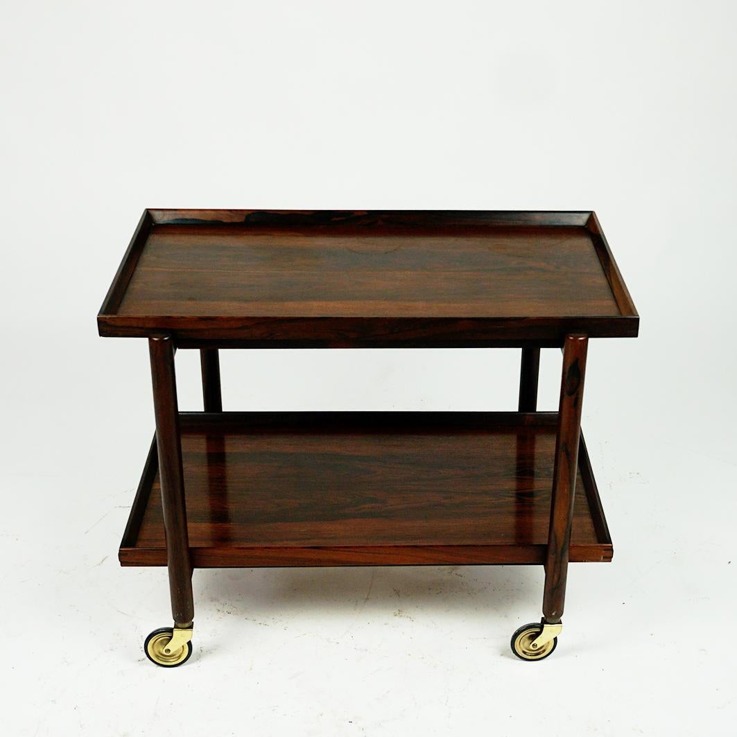 This excellent Scandinavian Modern rosewood bar cart or serving trolley has been designed by Poul Hundevad for VAD & Co Denmark in the 1960s, Mod. Nr. 23/2.
It is made of solid and venered Rosewood. The lower tray is removable and can be added to