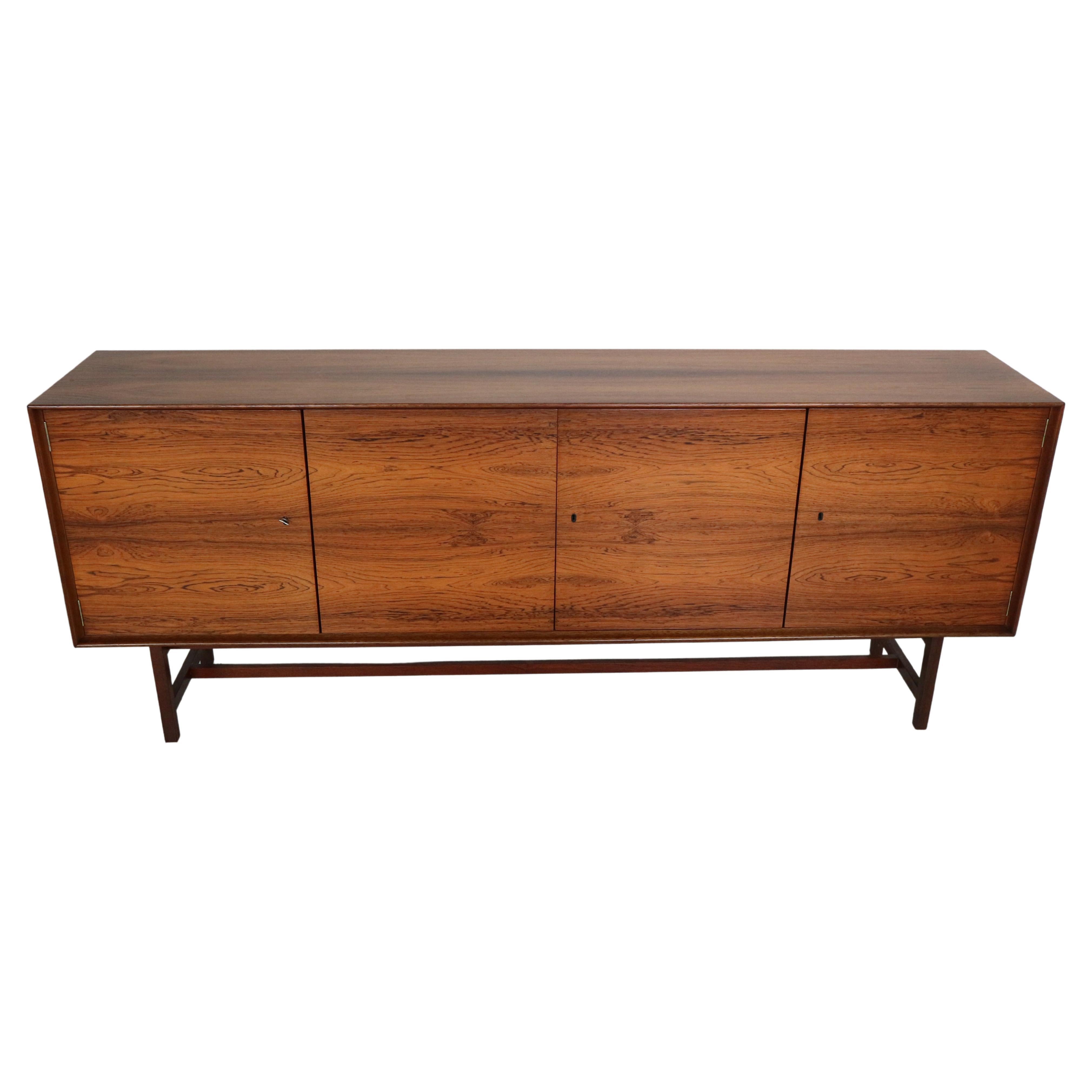 Scandinavian Modern period sideboard produced in 1960's Denmark. 
Four hidden oak drawers on the side and three doors from both sides.
Four shelves.
The patterns of the wood is very beautiful.
Rounded corners.
Solid frame and feet.
All the