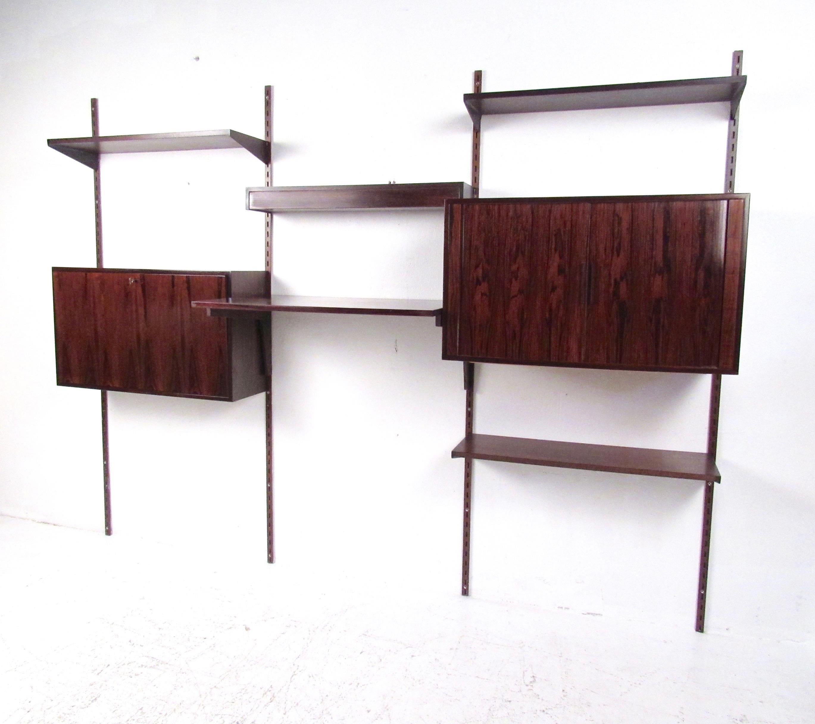 This striking vintage modern shelving unit features stunning rosewood construction with unique modular wall brackets. Scandinavian modern design in the style of Kai Kristiansen allows one to arrange the cabinets, shelves, and workspace to fit your