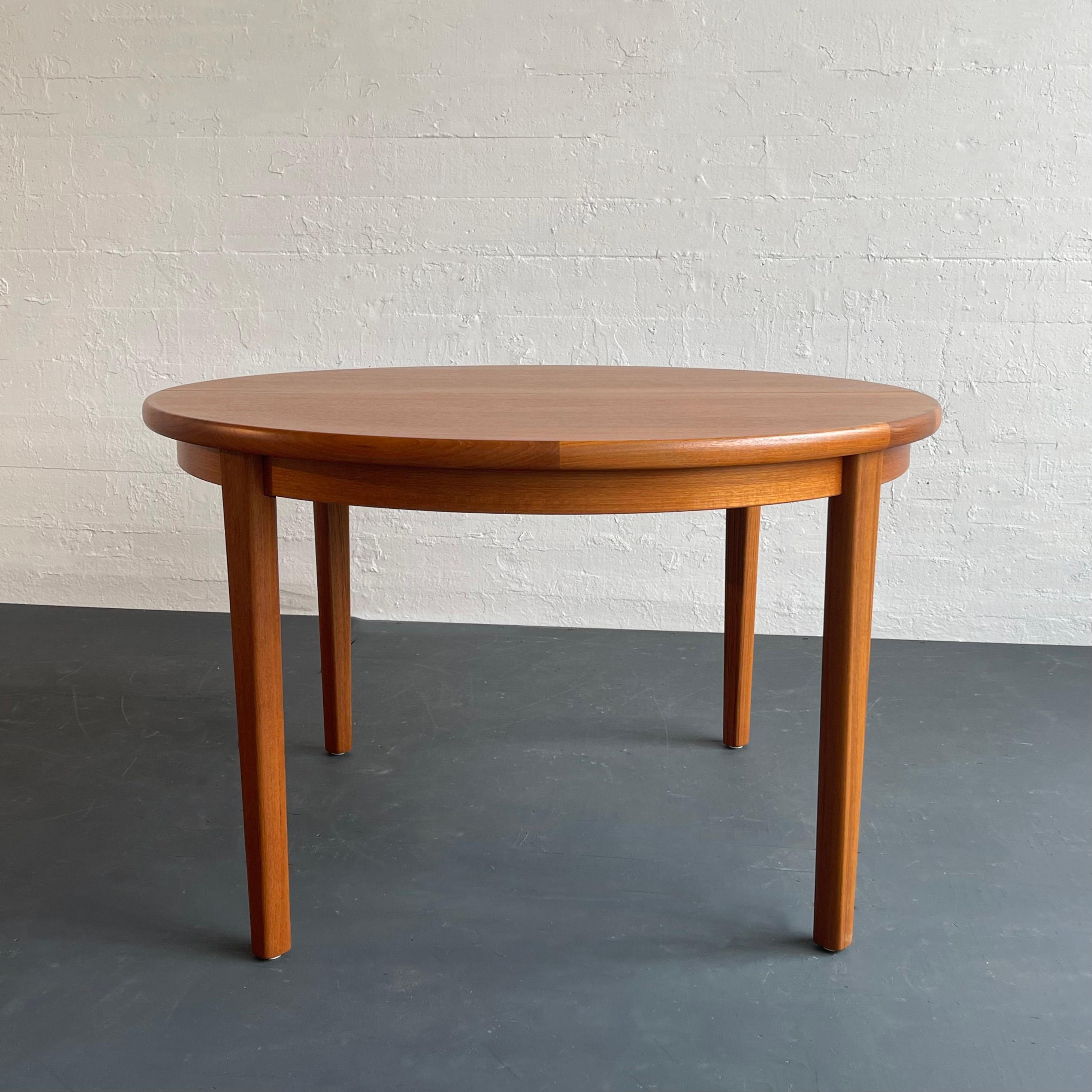 Beautiful Danish modern, solid teak dining table features a round top with contrasting trim and faceted legs.  The table has a wonderful natural honey-tone teak grain that is newly finished. It seats four people comfortably as shown with the Arne