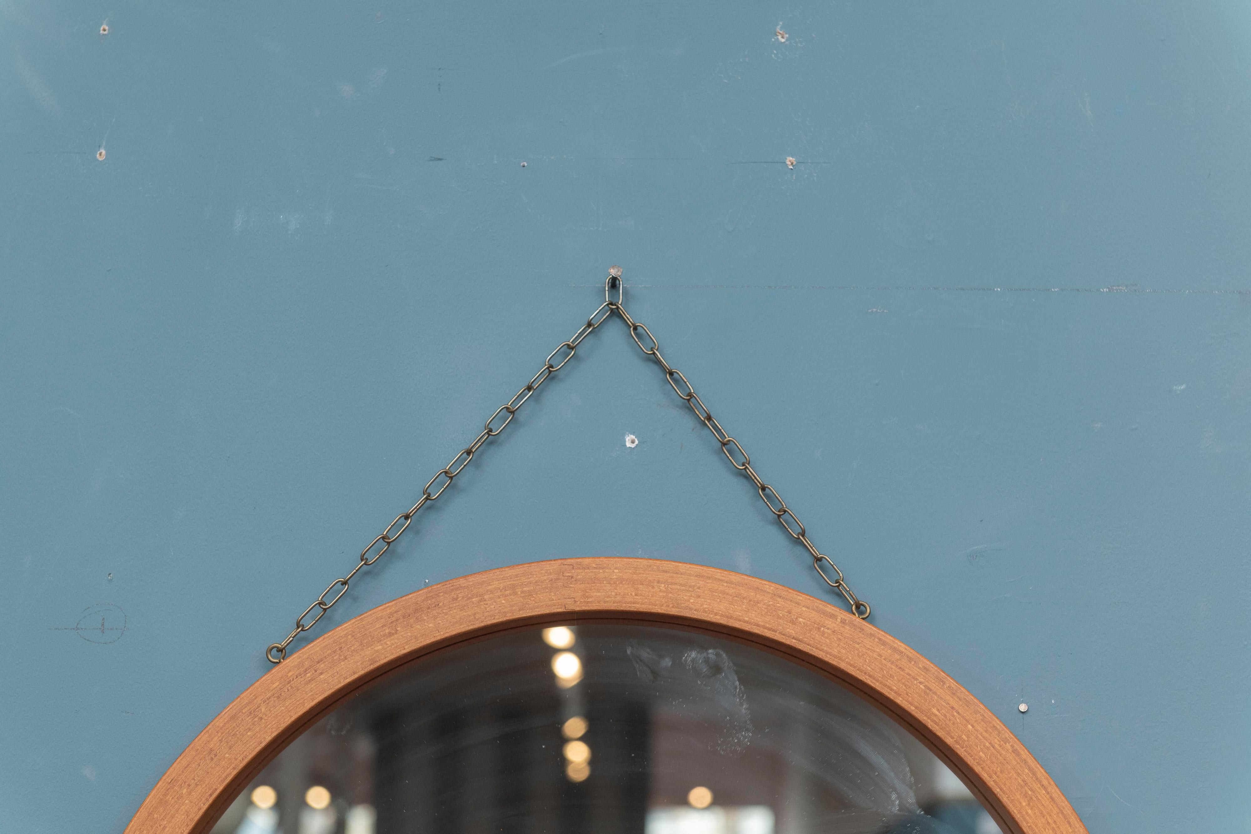 Runder skandinavisch-moderner Wandspiegel zum Aufhängen. Hergestellt aus ineinandergreifendem Teakholz-Sperrholz mit einer patinierten Messingkette zum Aufhängen.
