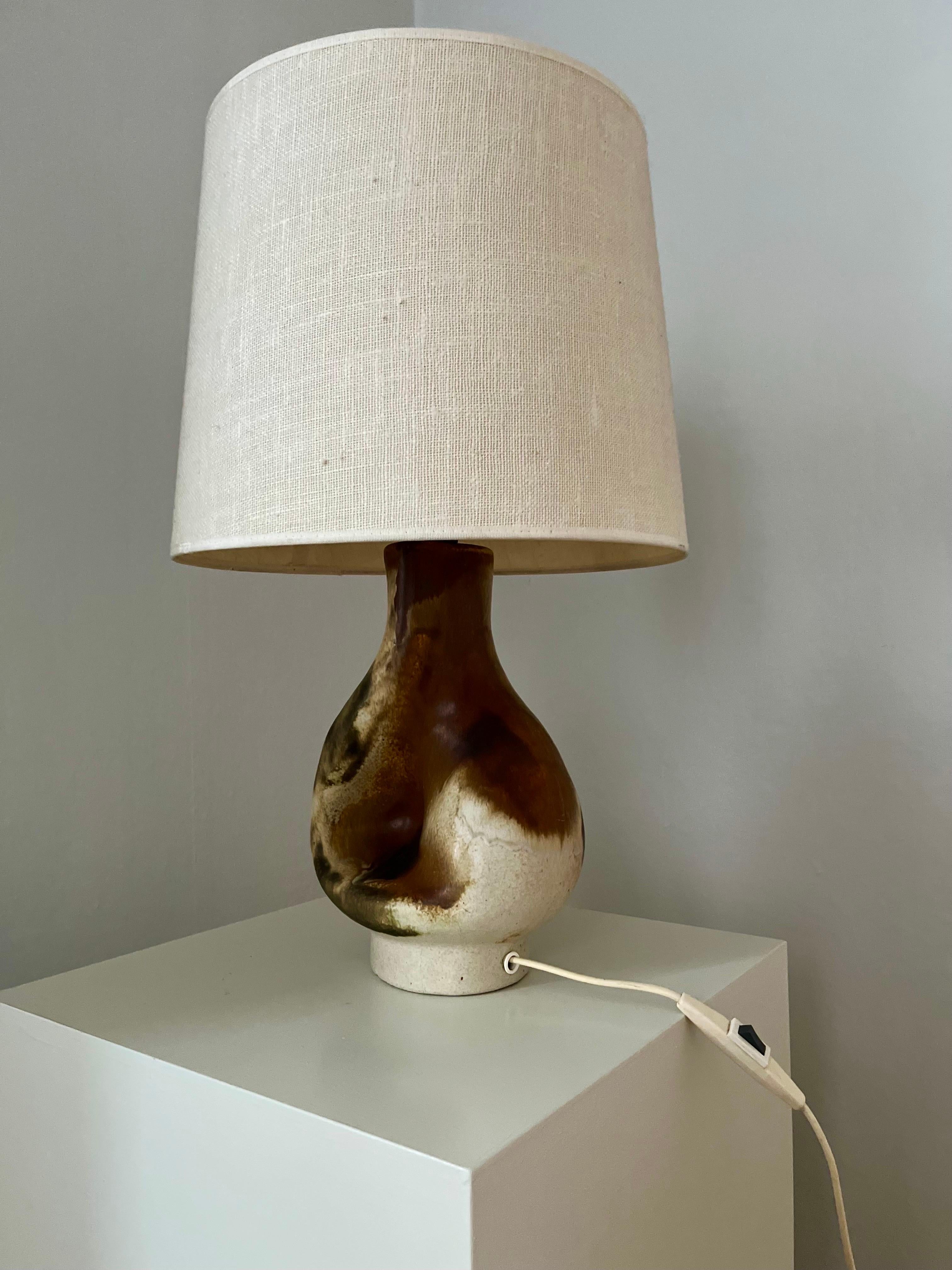 Scandinavian Modern sculptural stoneware table lamp by Danish Axella 1960s. 
This organic shaped, rustic and sculptural, almost deconstructed table lamp was made by Danish manufacturer Axella Stentøj in the 1960s. Decorations in nuances of brown.