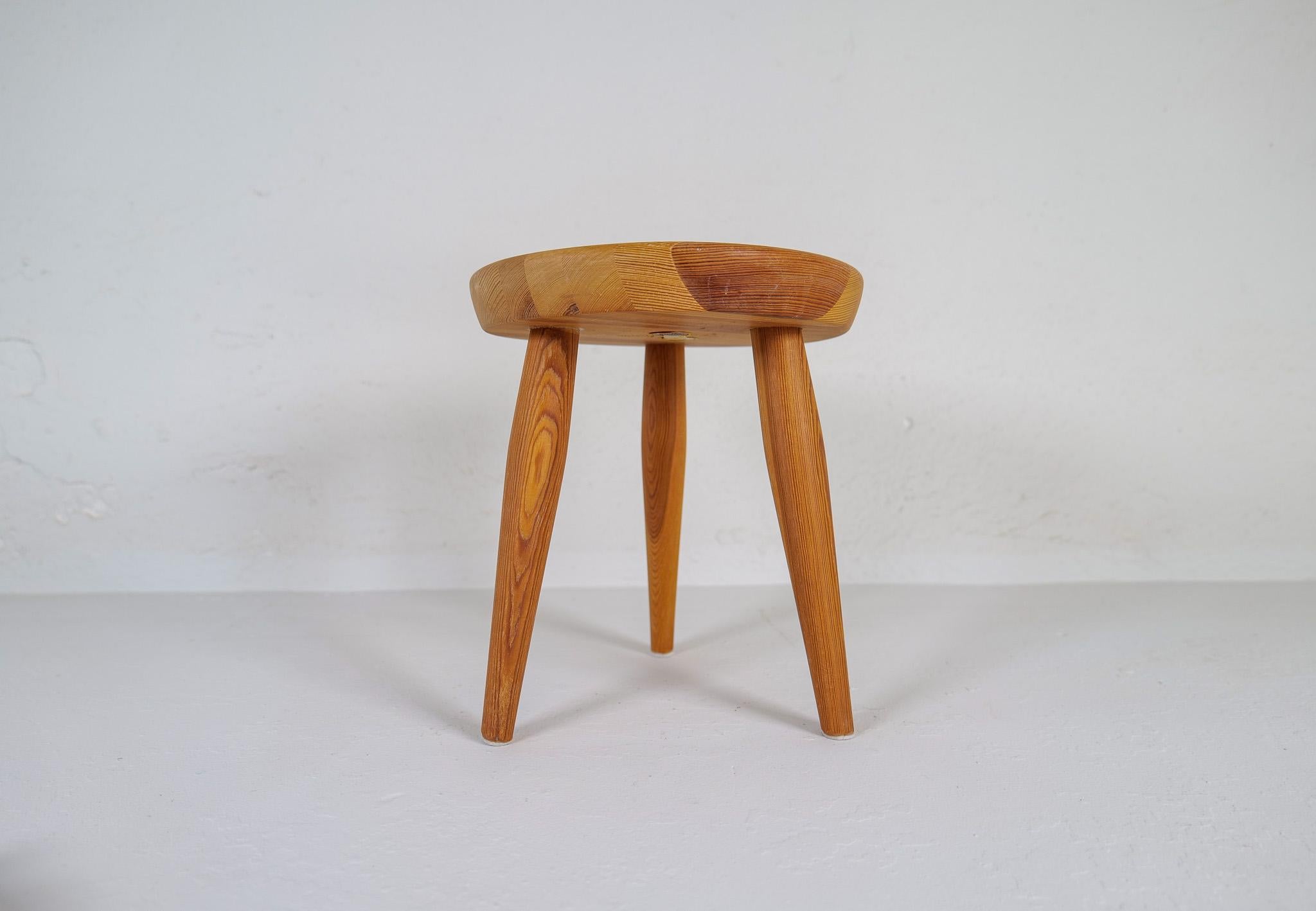 A small sculptural stool in solid pine with complexity in the different colors of the wood.
This stool is a good example of the good craftsmanship and minimalistic stile to come in Scandinavian furniture. 

Good original condition with a