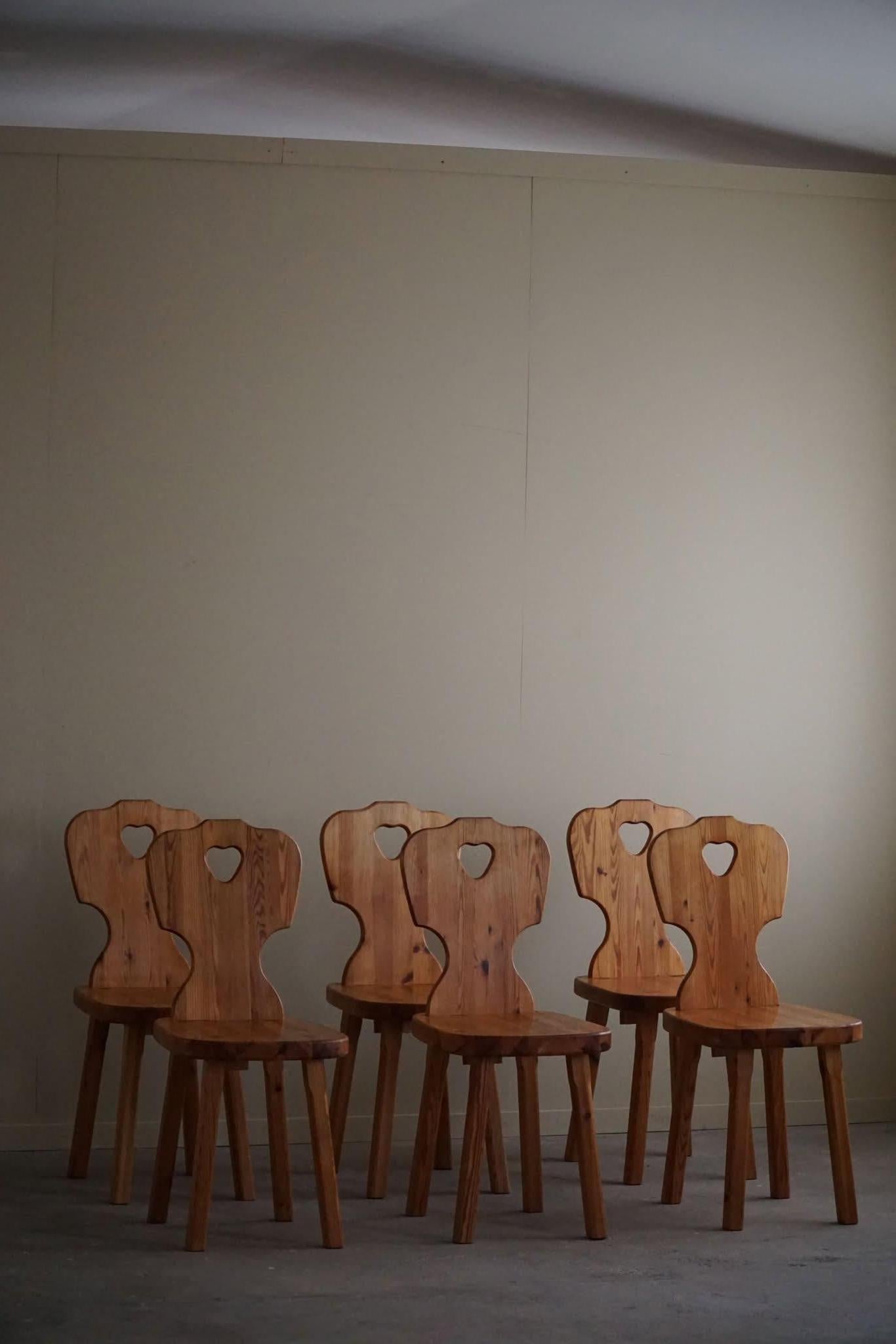 A beautiful set of 6 sculptural dining chairs in solid pine with a fine carved heart in the backrest and visible dowels. Hand-crafted by a Swedish Cabinetmaker in the 1960s. These dining chairs have a strong impression that pairs well with many