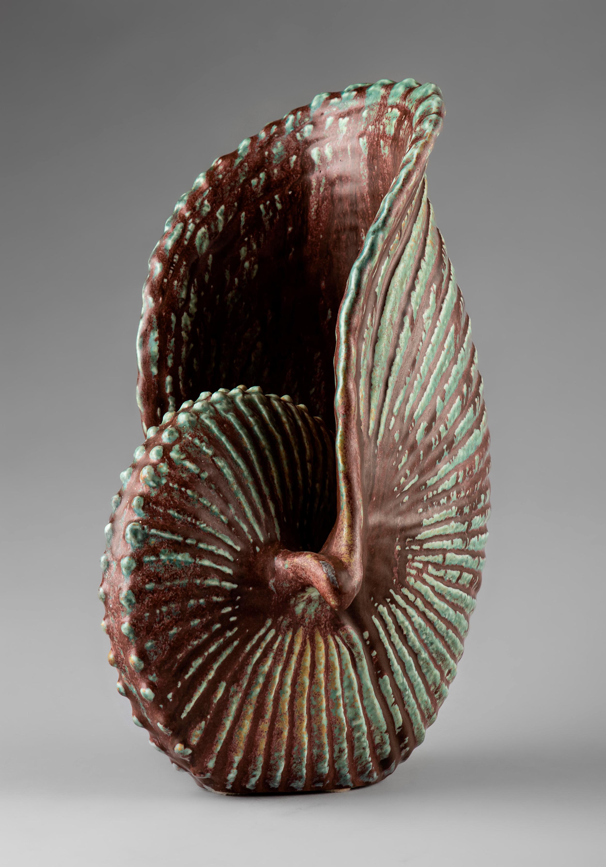 Stunning stoneware sculpture by Gunnar Nylund in the shape of a shell. Beautifully executed with close resemblance to a real shell. Muted green glaze with a thin grainy red glaze running like sand over the body.