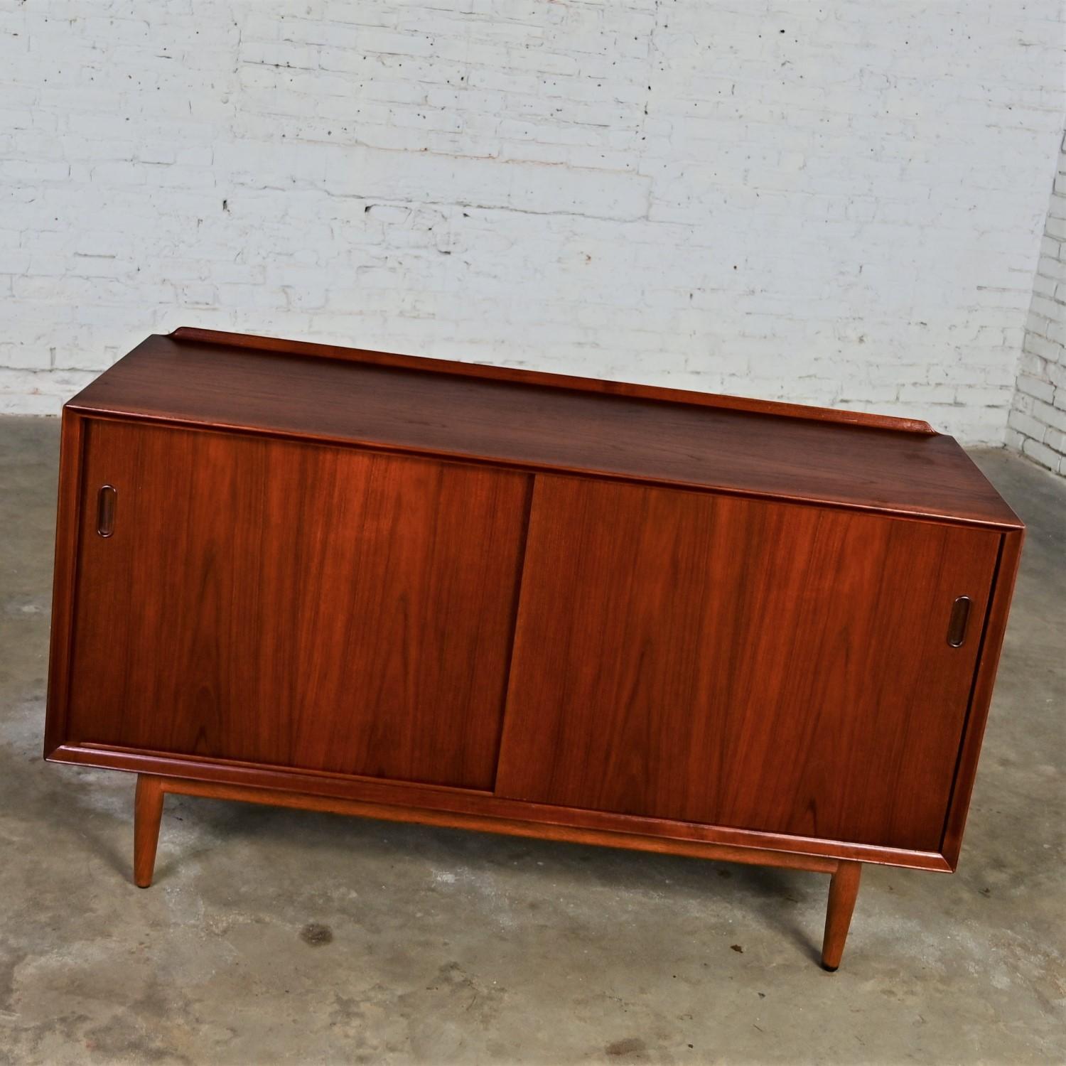  Handsome vintage Scandinavian Modern Sibast No 11 sideboard, buffet, credenza by Arne Vodder for George Tanier comprised of a teak frame, round tapered legs, light birch adjustable interiors, and sliding bypass reversible doors teak on one side and
