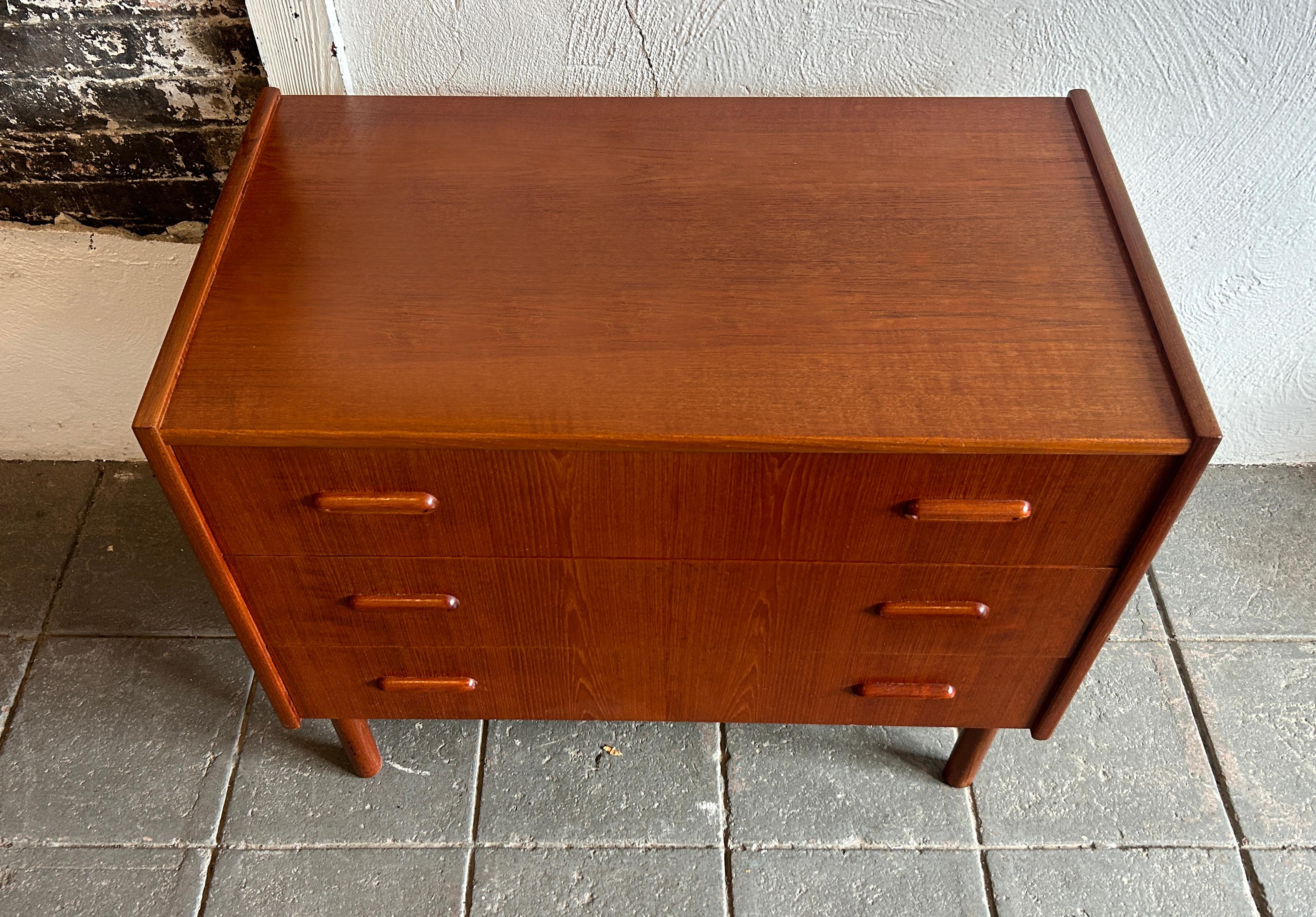 Mid Century Scandinavian Modern Small low 3 Drawer teak dresser made in Norway. Great red tone teak wood small dresser with carved handles and round cylindrical legs. Very nice construction with a beautiful wood grain. Nice simple Scandinavian