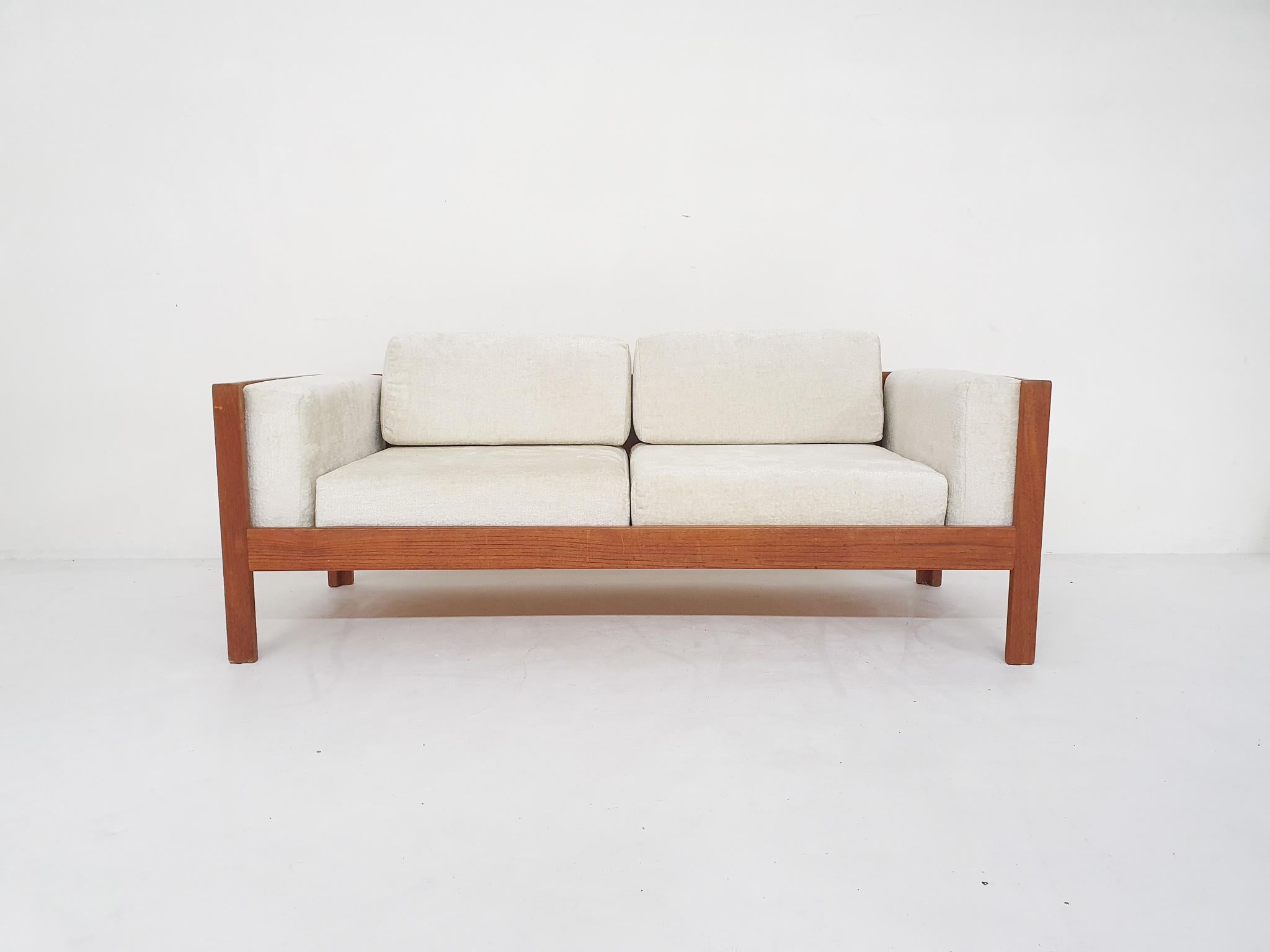 Two seater sofa in teak with loose cushions re-uphosltered in off-white boucle style fabric.
