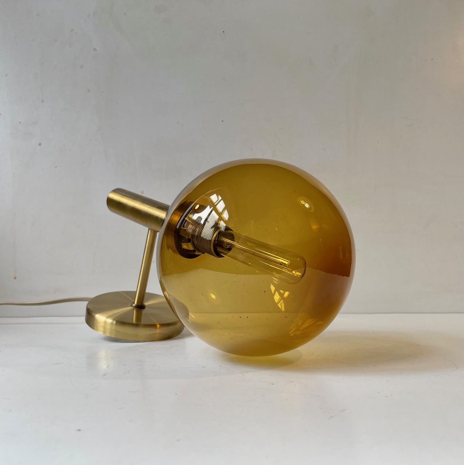 Lounge wall light with spherical honey colored shade in smoked glass. It was manufactured and designed by Vitrika in Denmark in a style reminiscent of Hans-Agne Jakobsson. Nice vintage and working order with a light patina to the brass frame. Fitted