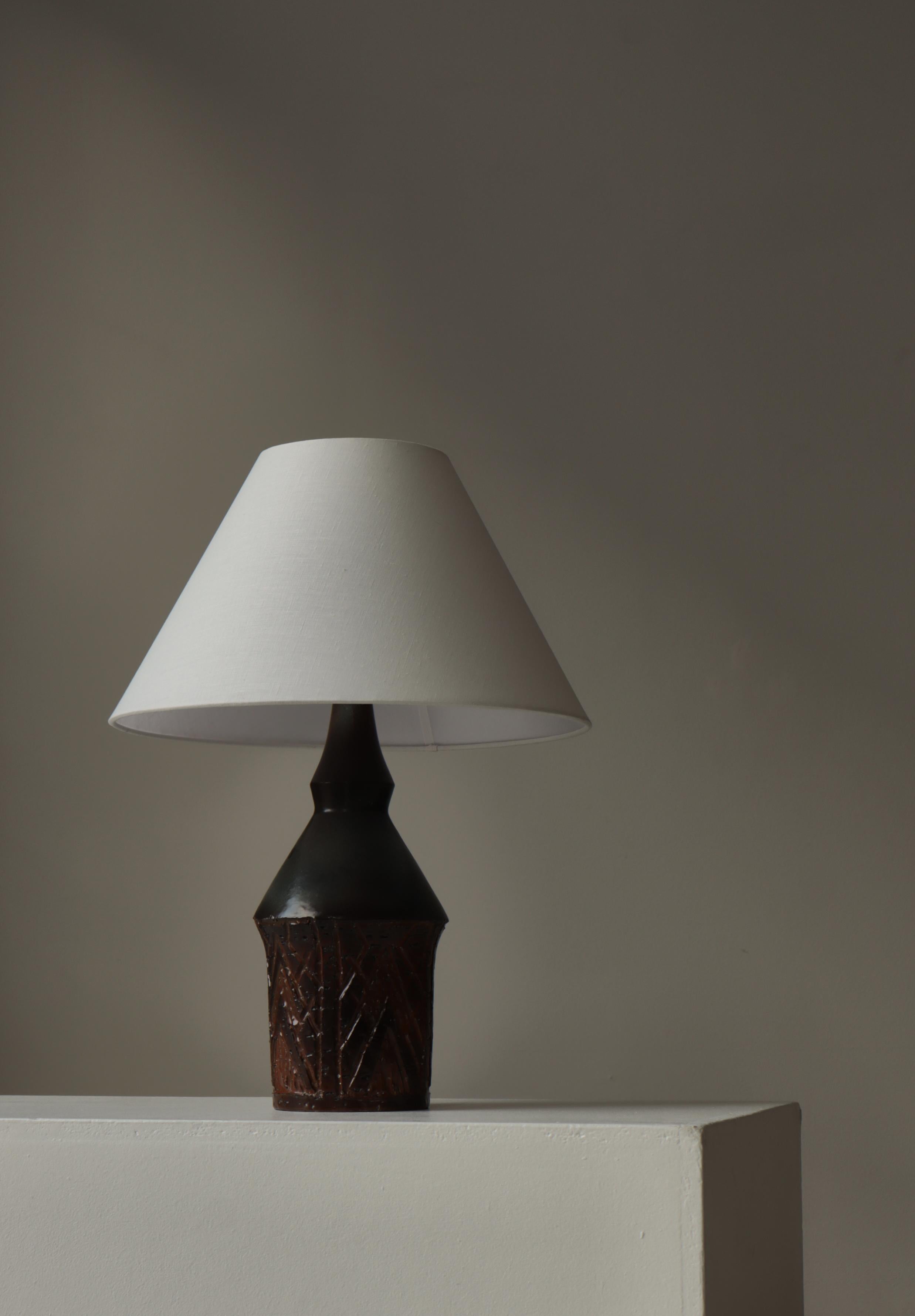 Exemple frappant de l'artisanat scandinave du milieu du siècle, cette lampe de table en grès cultivé à la main des années 1960 par Sejer Denmark présente un riche jeu de textures, de glaçures et de formes sculpturales. La base présente un relief