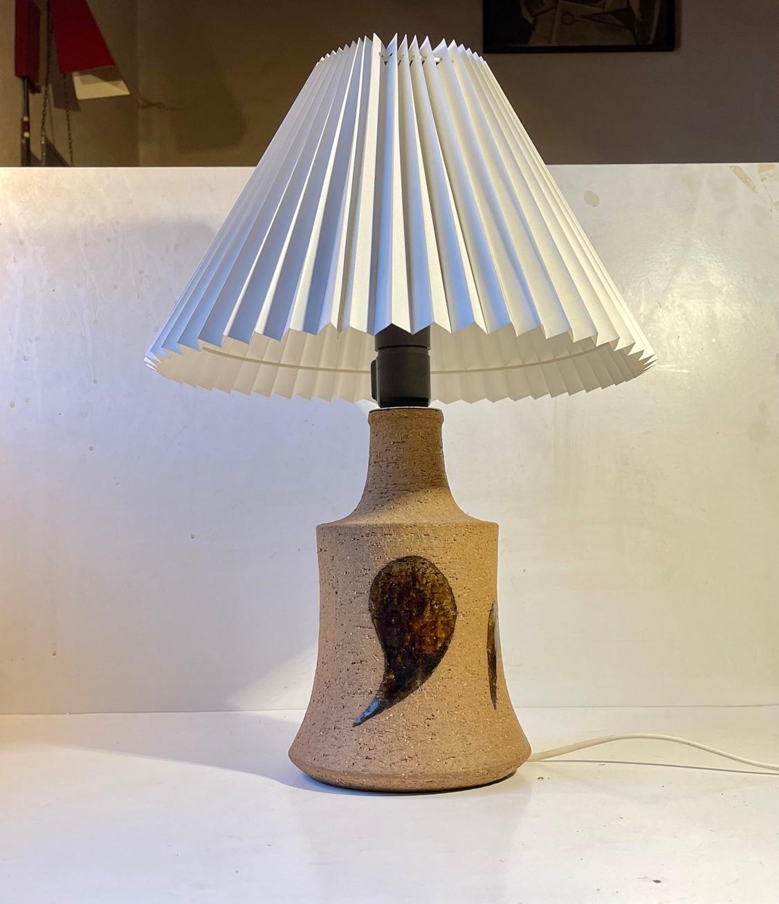 A large stoneware stable lamp by the popular Danish ceramist Eigil Henriksen. It is executed in unglazed chamotte clay and decorated with brown monochrome leaves. It features an on/of switch to its socket and retains its original circuit and cord.