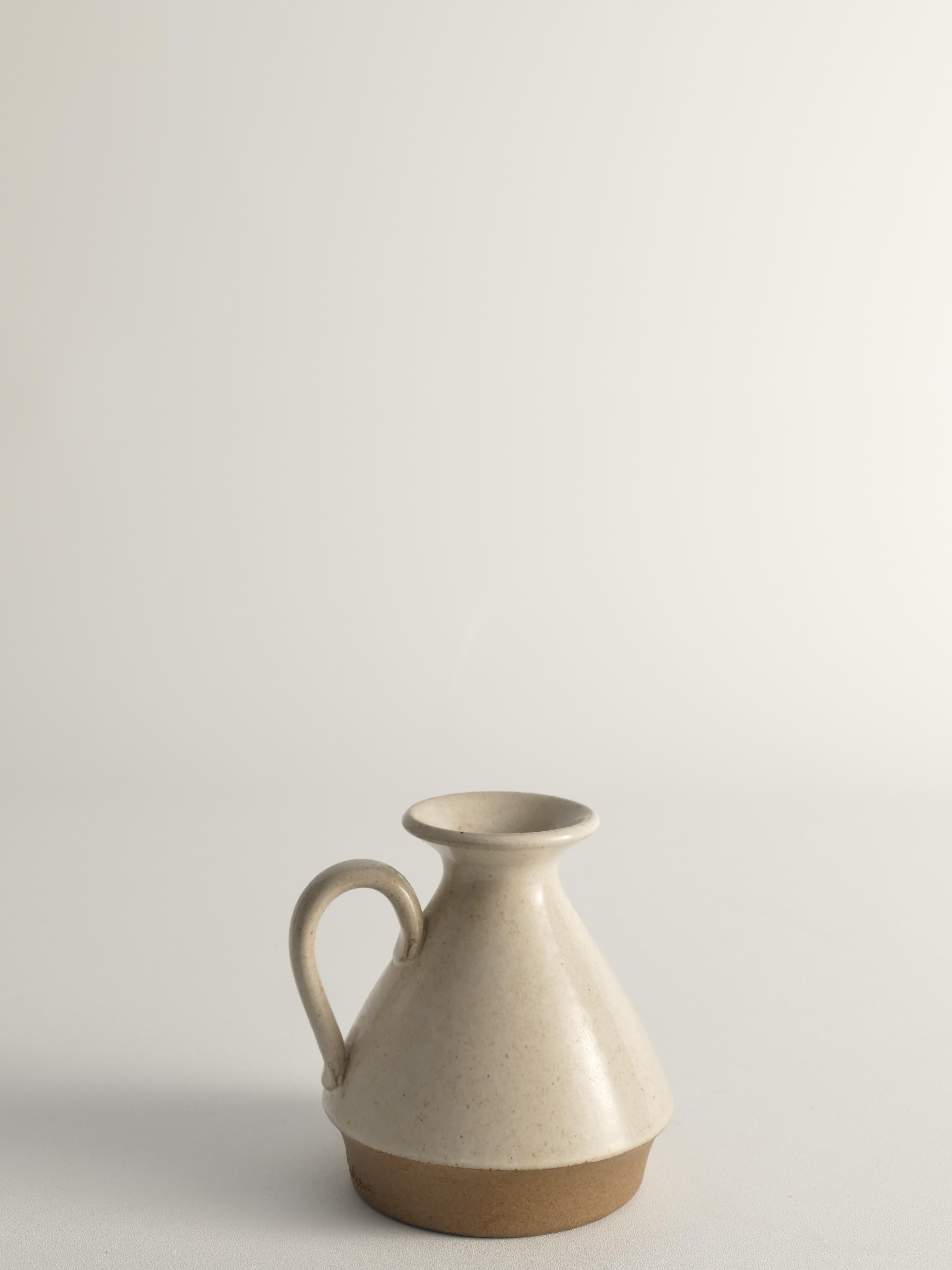 Vaso moderno scandinavo in gres Selsbo con smalto marrone e guscio d'uovo, firmato da Aage Rasmus Selsbo.
Questo vaso in gres ha una forma conica, tipica del design moderno scandinavo, e un manico sottile. Il vaso presenta una base marrone non