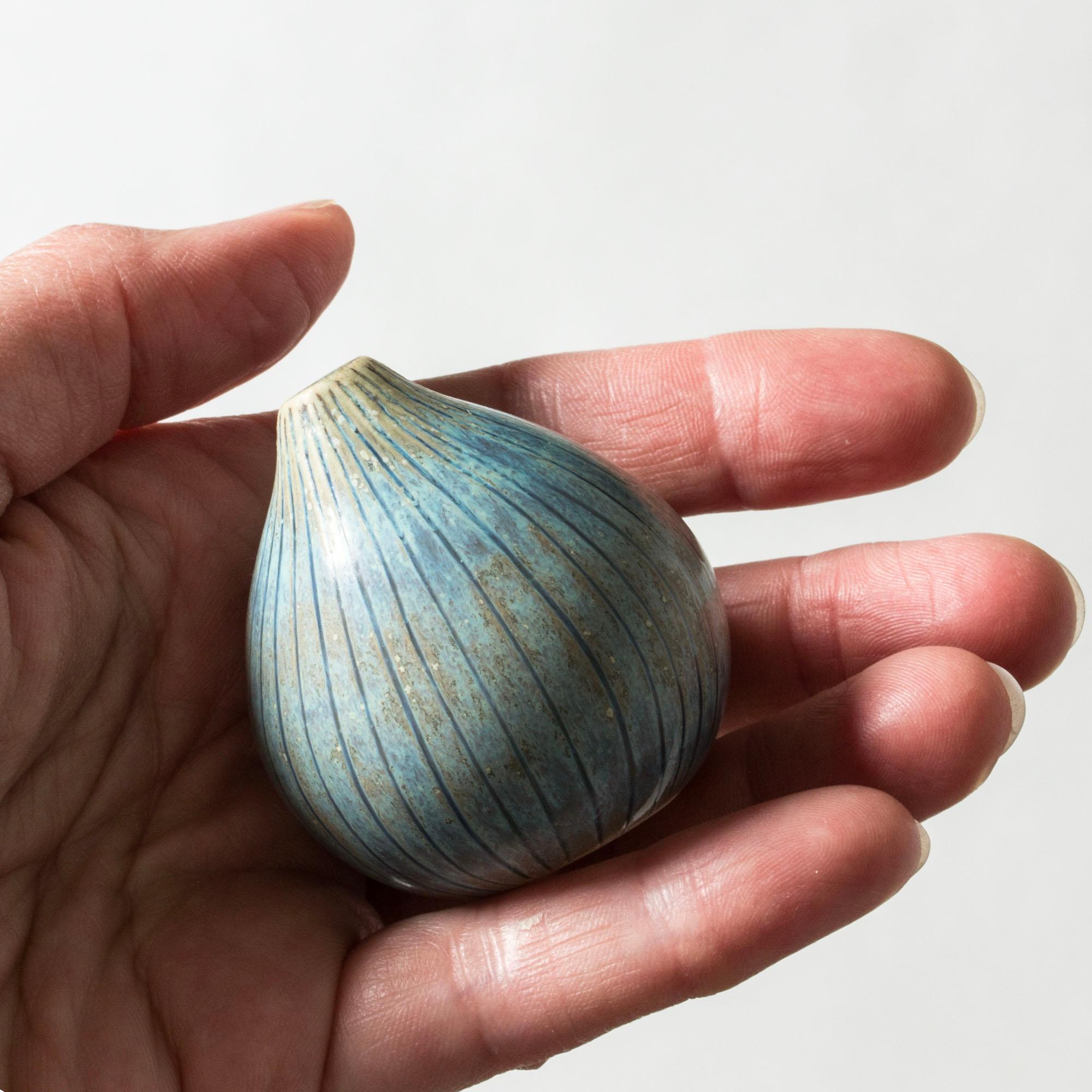 Lovely, unique miniature stoneware vase by Stig Lindberg, formed like an onion with a slightly asymmetric shape. Embossed striped pattern, glazed light blue and clay.