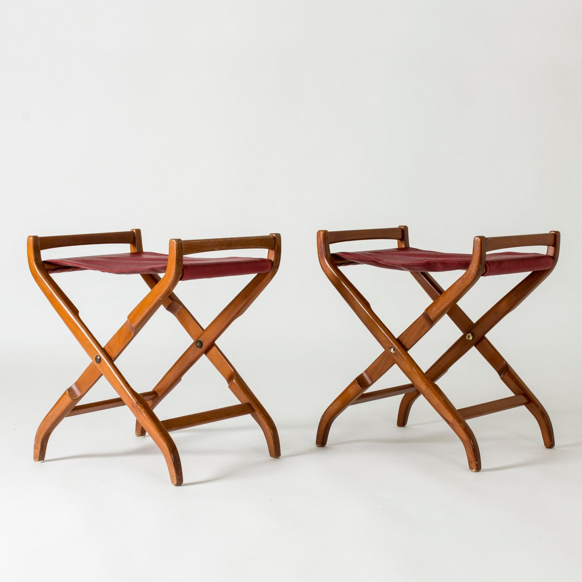 Pair of beautiful mahogany stools by David Rosén, with dark red leather seats. Possible to fold.