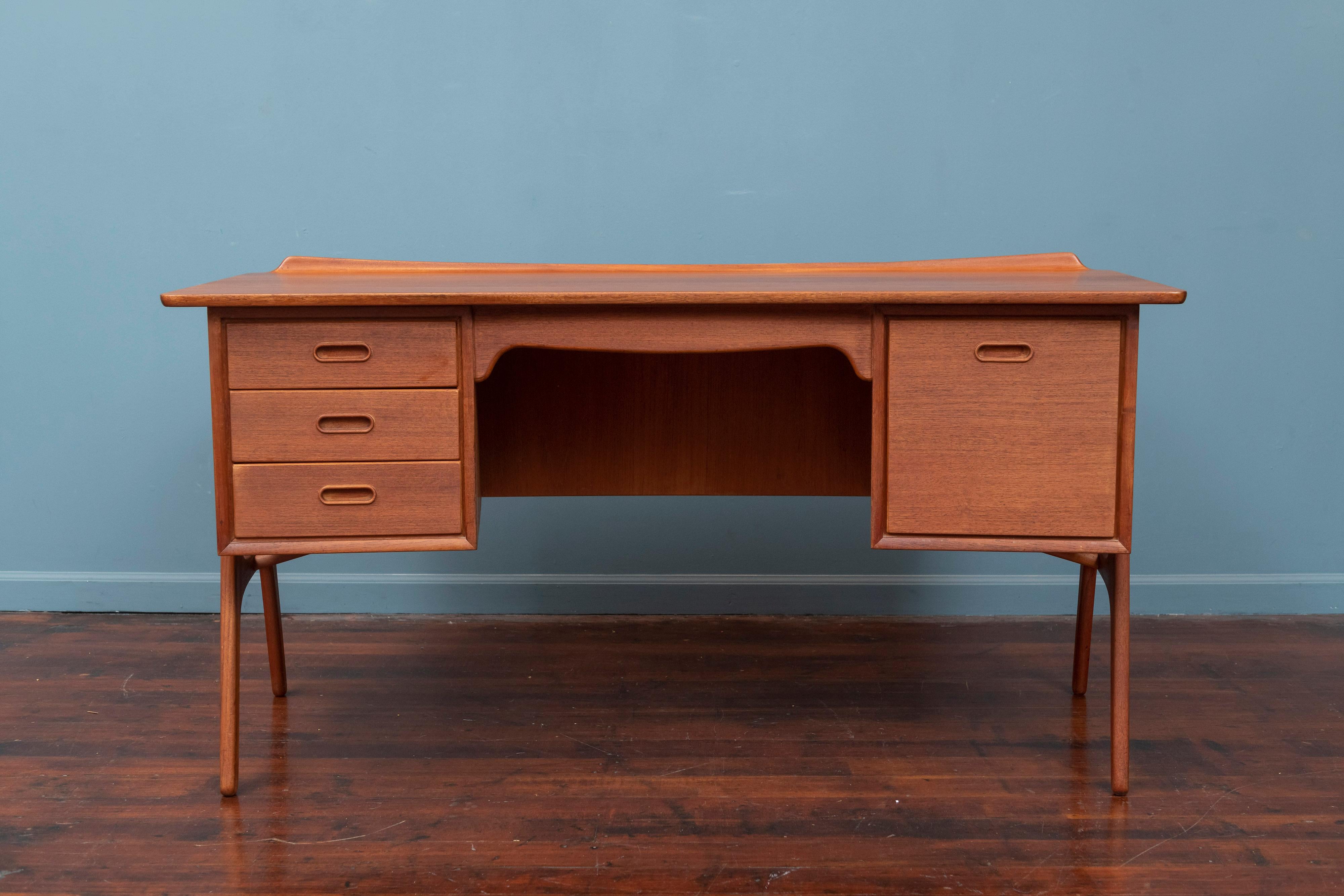 Scandinavian Modern desk designed by Svend Aage Madsen for Sigurd Hansen Mobelfabrik, Denmark. Having a curved teak case with sculpted trim edges to catch a pencil or paper and three small drawers on the left and a file drawer on the left. Open