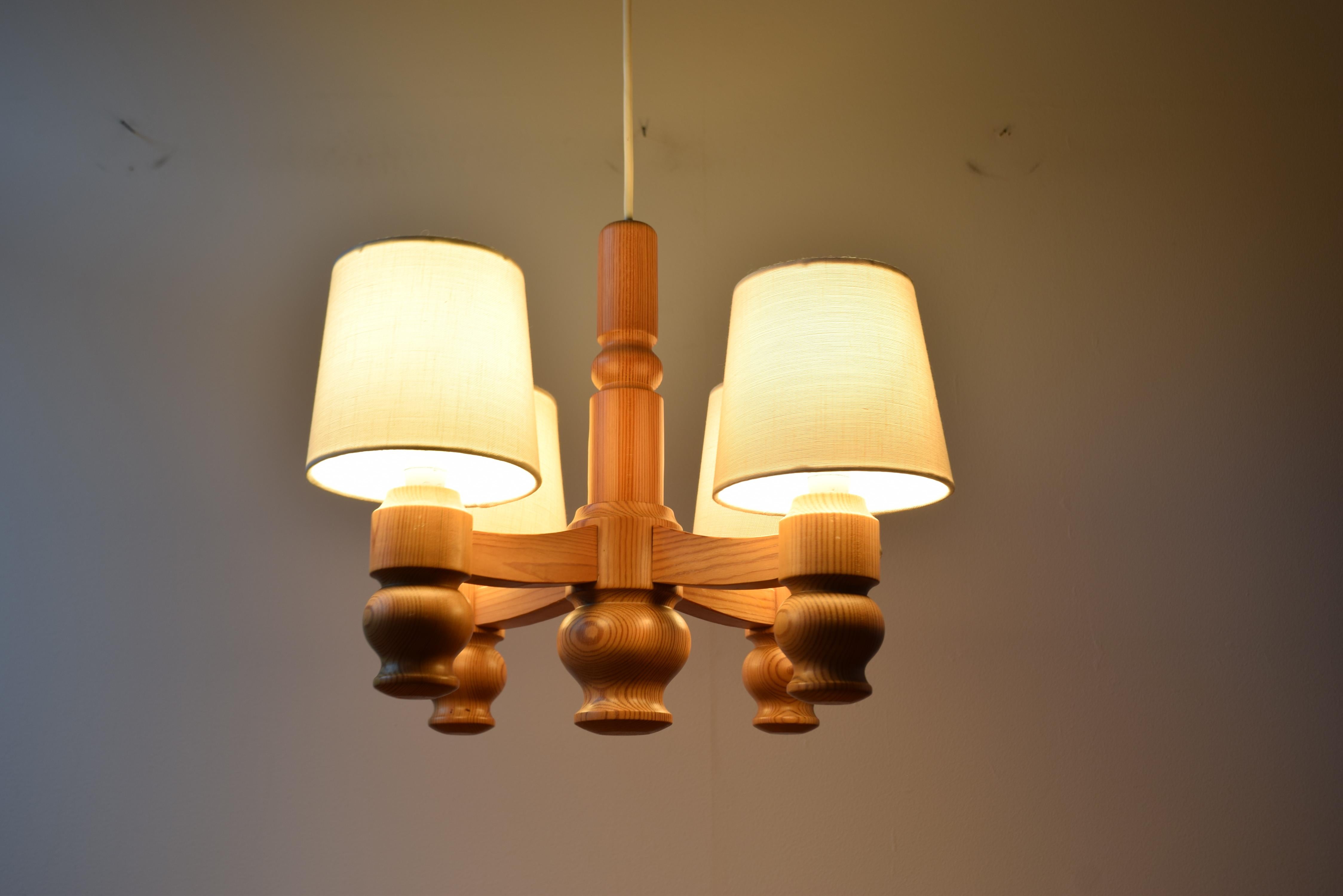 Un lampadario moderno scandinavo in pino massiccio prodotto in Svezia negli anni '70.
I piccoli paralumi in tessuto sono realizzati con un tessuto simile al lino bianco sporco, aggiunto da noi e prodotto in Danimarca. 

La lampada utilizza lampadine