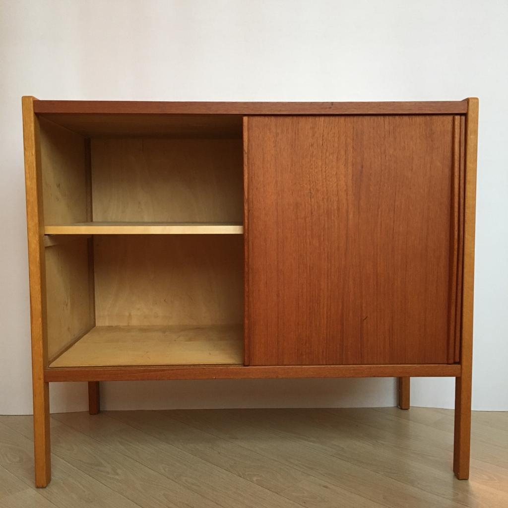 This Mid-Century Modern sideboard is made of teak wood and features sliding doors and nice brass details on the sides. It is very minimalistic and looks great in the interior.
It has some spots on the desk but they are almost invisible. The inside