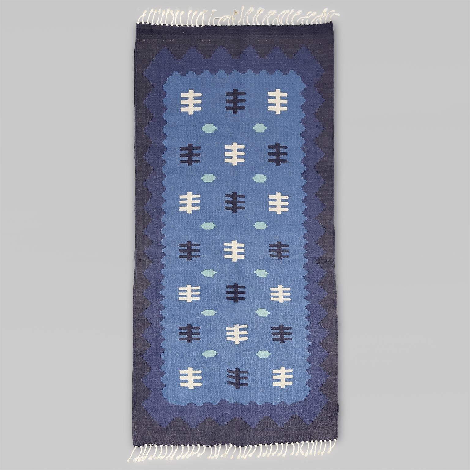 Scandinavian Modern, Swedish Mid-Century Modern wool flat-weave rug with a graphic design in light, medium and dark blue, finished with white fringe. Professional cleaned.
 
Measures: Measures: Length 71”, width 35”.
  