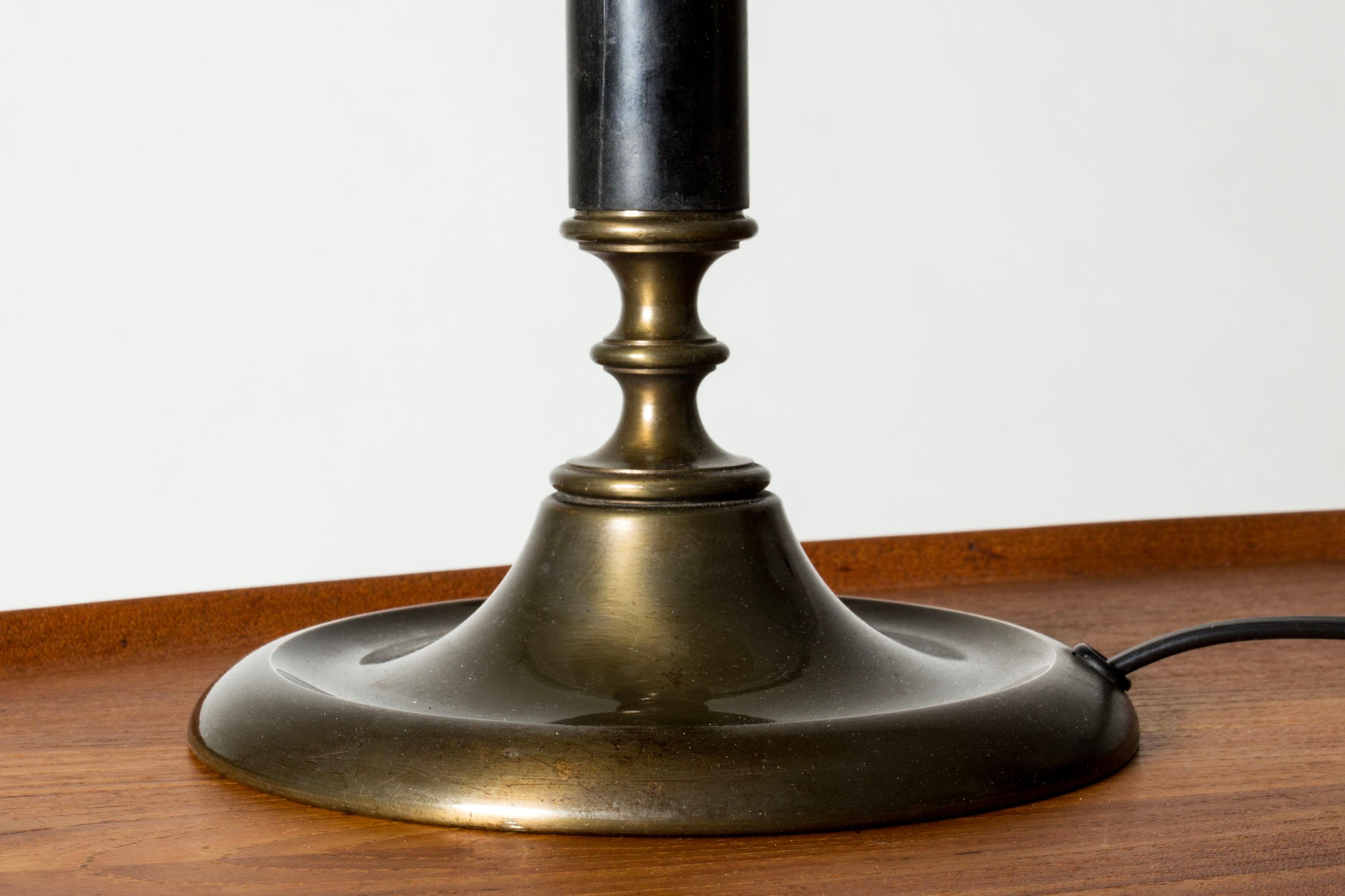 Lovely table lamp from Böhlmarks, made from brass with a large shade lacquered dark green. The key detail on top of the shade lights the lamp when turned.