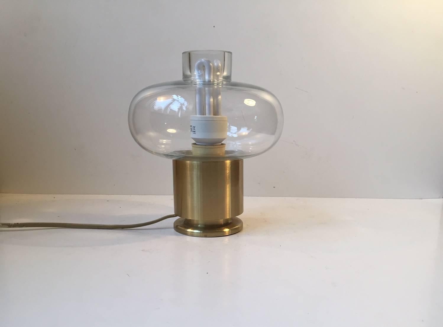 Small table light composed of brass and thick clear glass. It was manufactured by Fog & Mørup in Denmark in the early 1970s. The base is labeled with makers mark from F&M. The style of this light is strikingly reminiscent of Hans Agne Jakobsson.