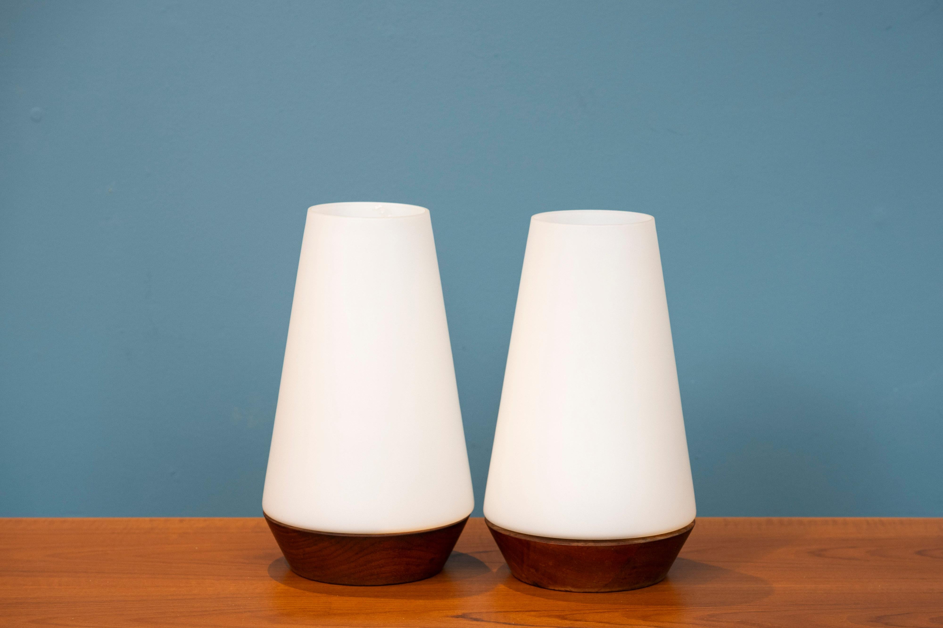 Scandinavian Modern table lamps, Sweden. Elegant shaped pair of table lamps with blown art glass shades on carved solid teak bases. In very good original condition, medium to larger size for these type of lamps.
