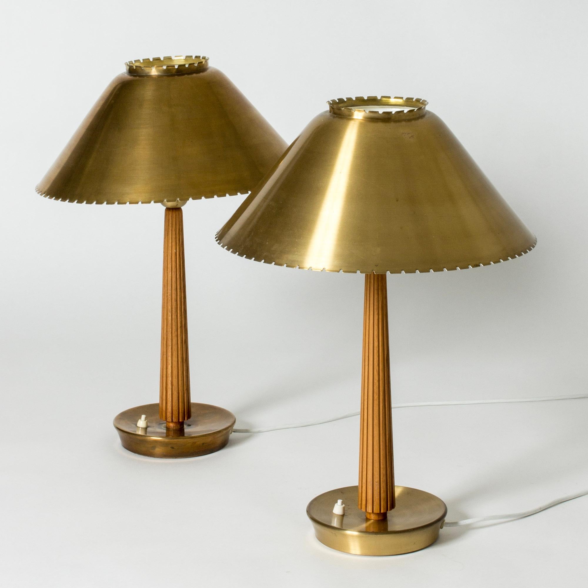 Pair of beautiful table lamps by Hans Bergström, made from brass and mahogany. Scalloped edges around the top and bottom of the shades. Handles embossed with decorative stripes.

Hans Bergström was the owner and creative director of the lighting