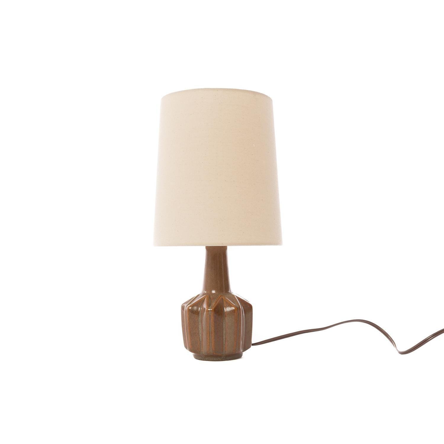 This diminutive table lamp has a channeled, star shaped base with a wheat and pumpkin colored glaze. New natural linen shade, brass switch and updated North American wiring. Artist-signed, 1952. Base is 4