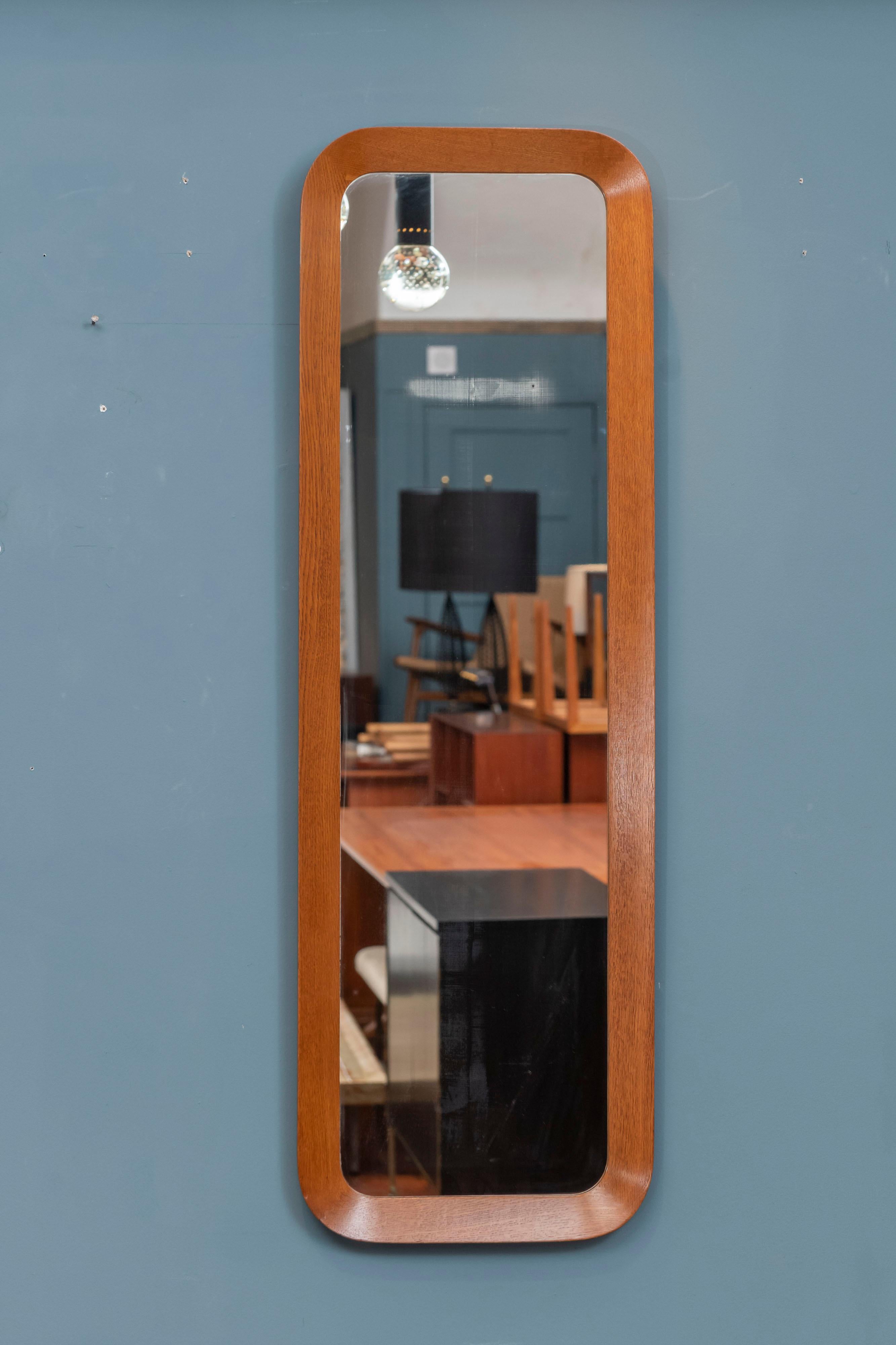 Scandinavian modern wall mirror made by AB Glas & Tra, Denmark.
 Newly refinished high quality construction solid teak wood frame with dovetail joinery at the corners and a shaped conclave frame, signed. 
Original mirror plate shows signs of age