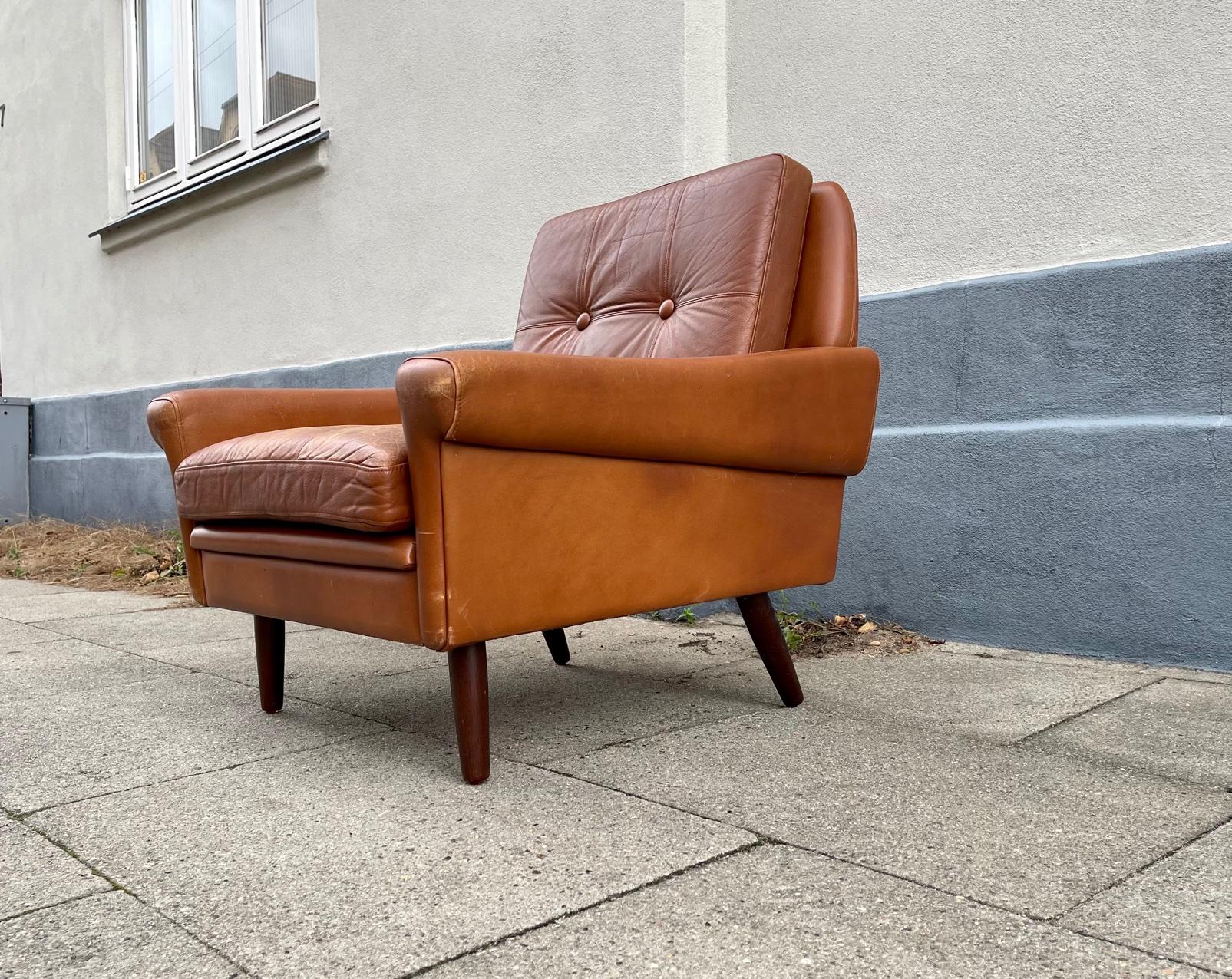 Lowriding (38 cm) all original Georg Thams lounge chair designed during the mid 1960s and manufactured at Thams Møbler in Denmark. This example retains its original soft brown cognac/tanned leather. It has tapered legs in solid teak.