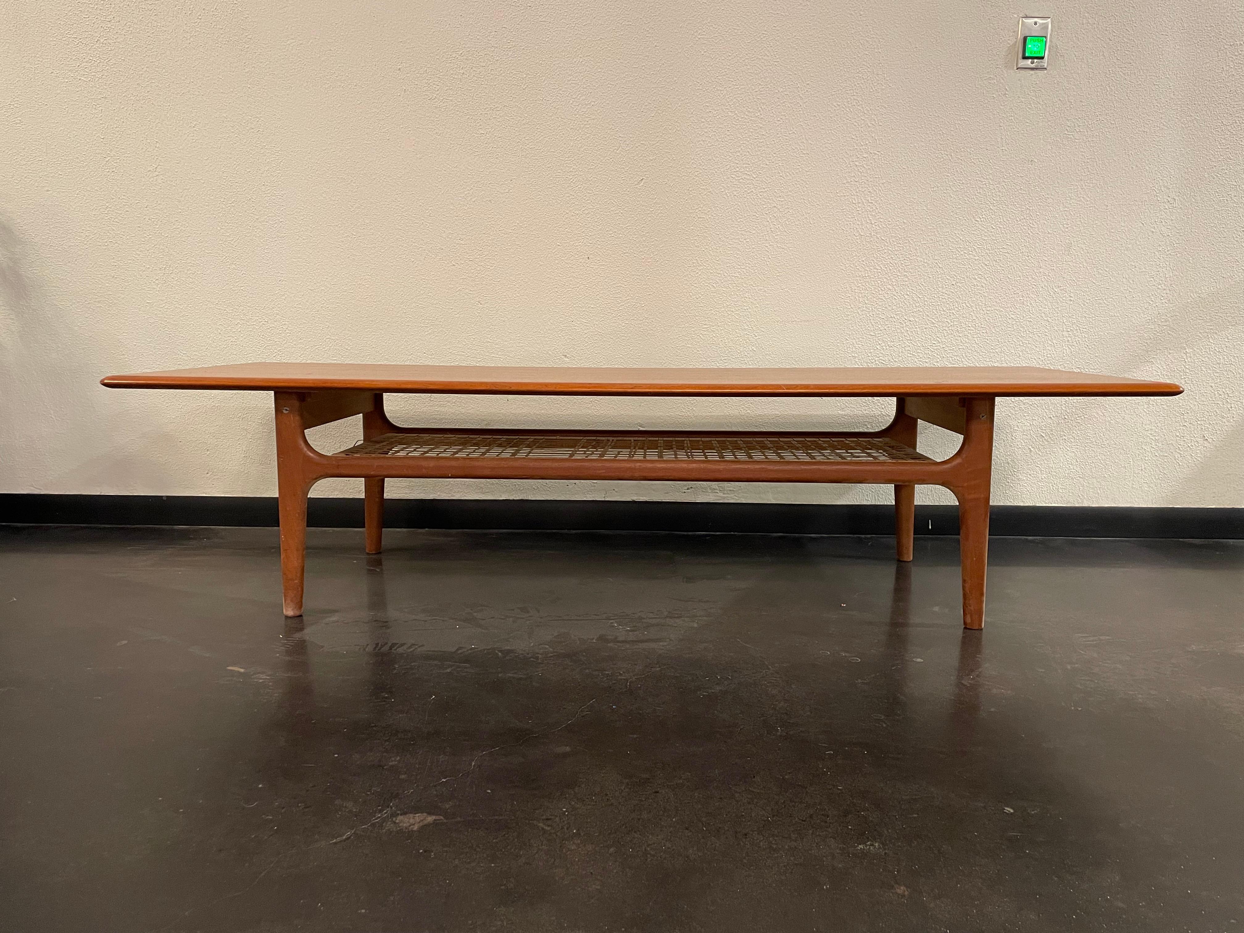 Beautiful Scandinavian Modern teak and Cane coffee table by Trioh Mobler. Cane shelving underneath table top for added storage.