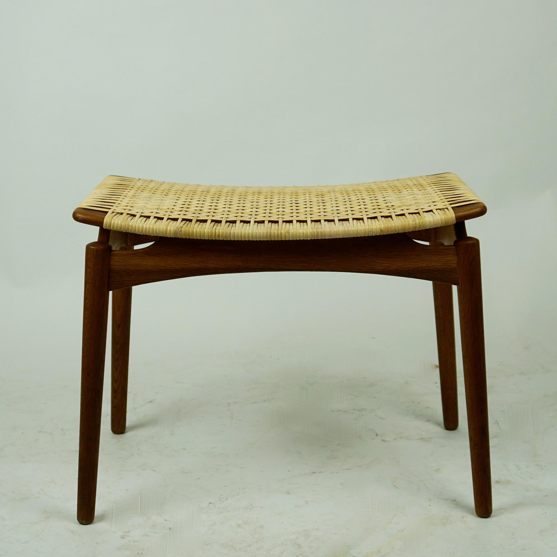This stunning midcentury stool with teak legs and new woven cane seat has been produced by Olholm Mobelfabrik Denmark in the 1950s.
It´s floating seat has been fully restored with slender thin strips of cane woven around. 
Lifted from the main legs