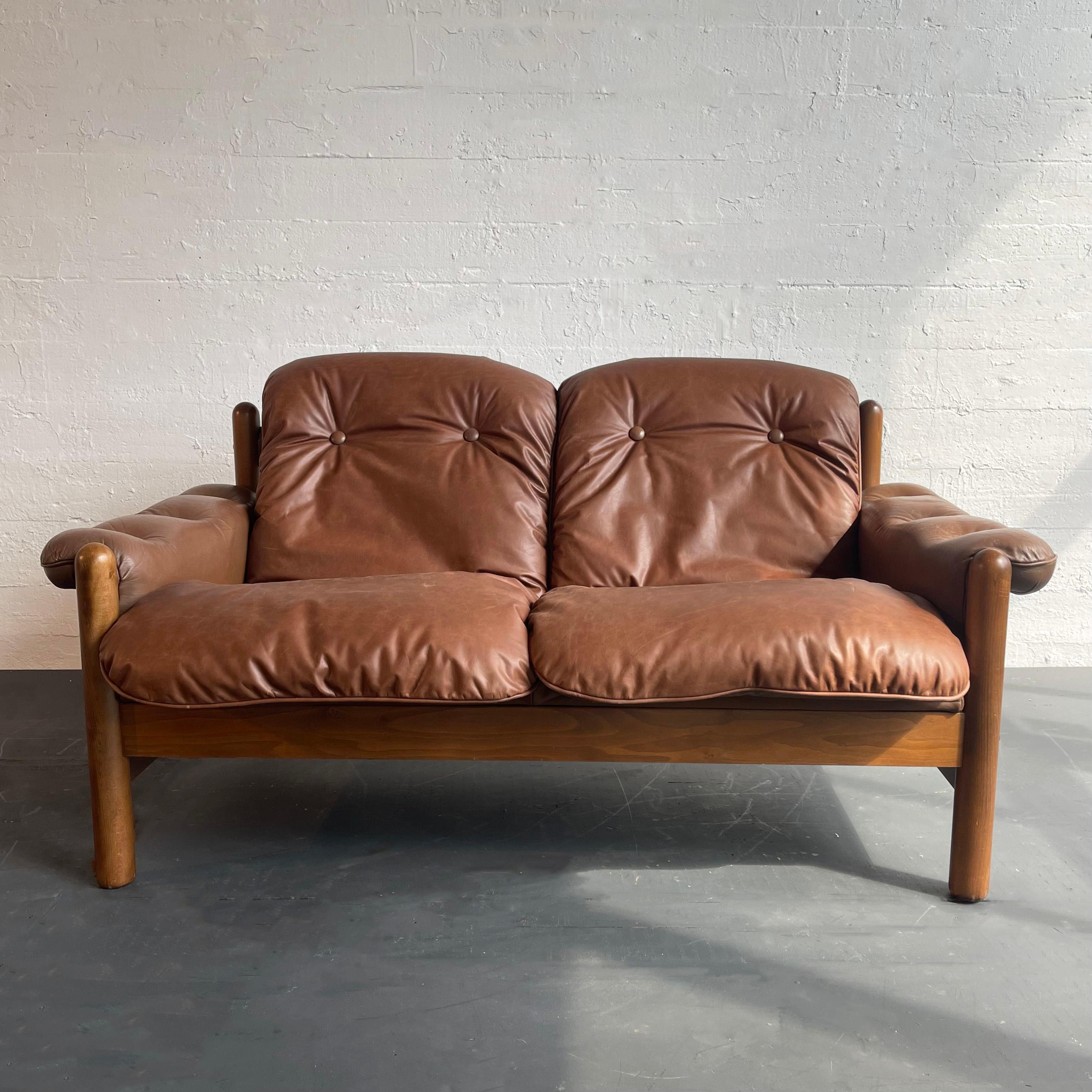 Scandinavian modern loveseat sofa in the style of Pierre Chapo features a thick teak frame with two newly upholstered, button-tufted leather cushions that lay within the frame and matching leather armrests at 20 inches height. The original leather