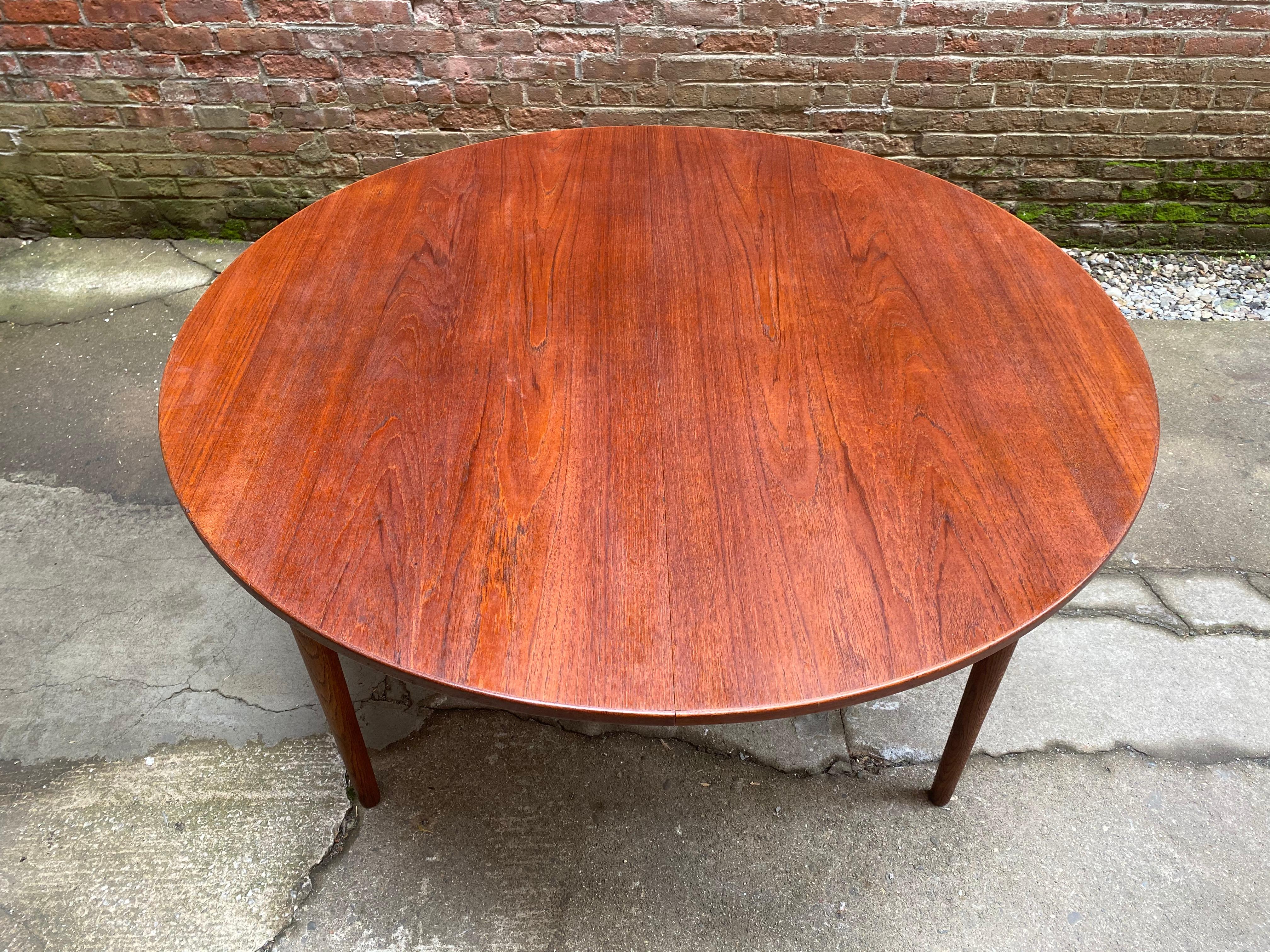 Scandinavian design teak and oak dining table with one large leaf, circa 1960-1965. Teak round top with tapered solid oak legs. Freshly oiled. Good condition overall with the runners sliding easily, some minor light scratches and some bruising on