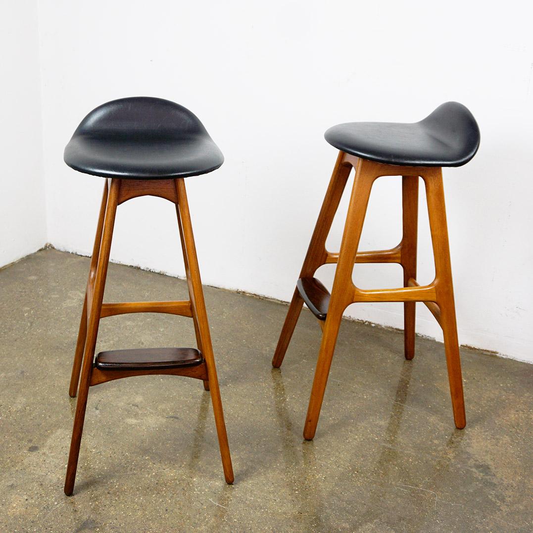 This set of two danish teak Mod. 61 Barstools with black leather seats has been designed by Erik Buck for Oddense Maskinsnedkeri Denmark 1960s. 
Manufacturers Label on the underside. These stools are one of the most sought after barstools and in