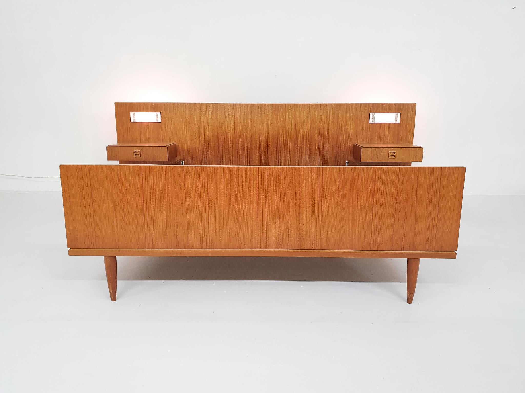Teak bed 140 x 200 cm, with a teak headboard with integrated nightstand and bed side lamps.
Headboard is 250 cm wide.