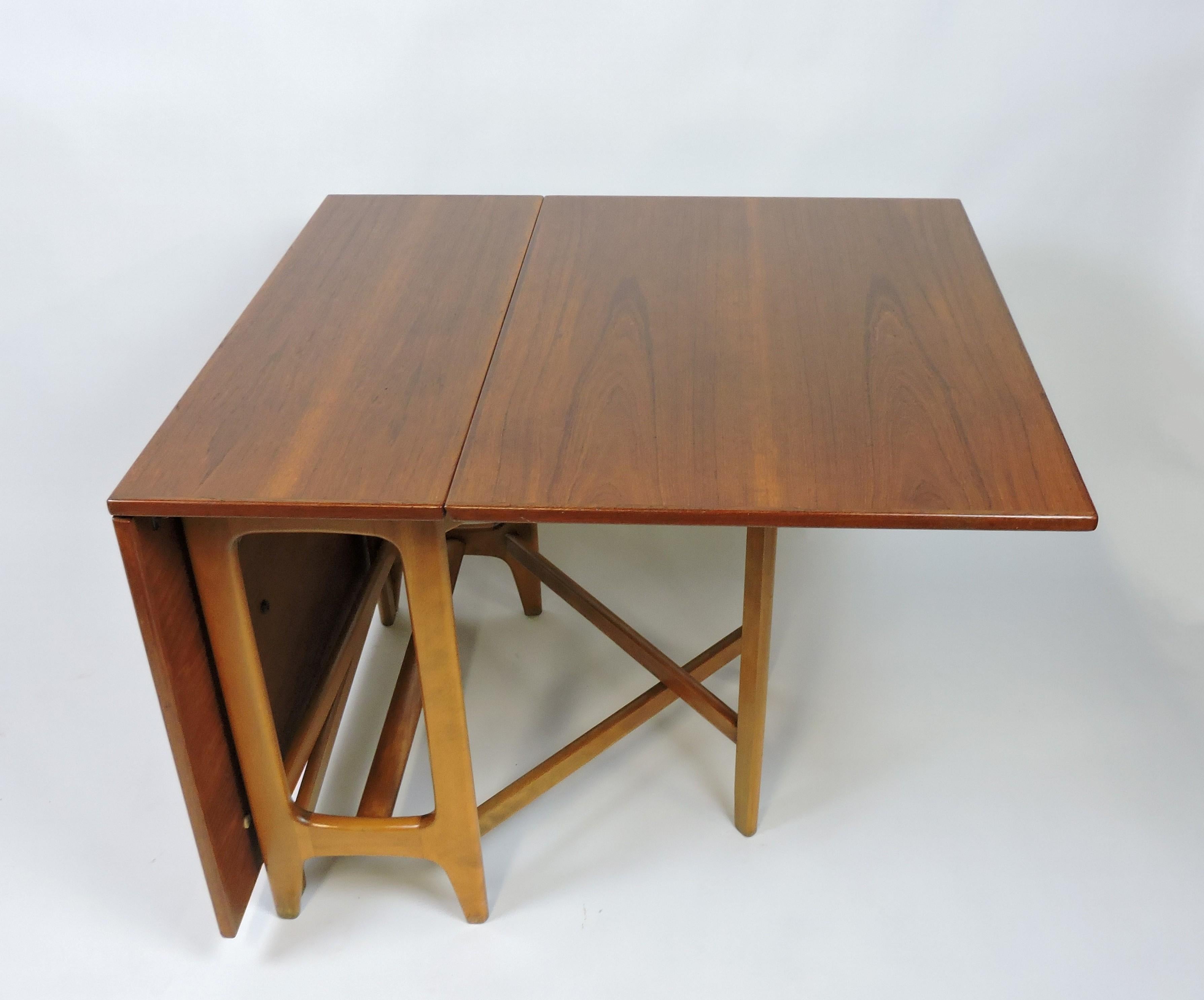 Beautiful Scandinavian modern teak drop leaf dining table designed by Bendt Winge and made in Norway. This table has sculpted solid beech legs and two drop down leaves that extend the surface area from 13.5 inches when closed to 64 inches when fully