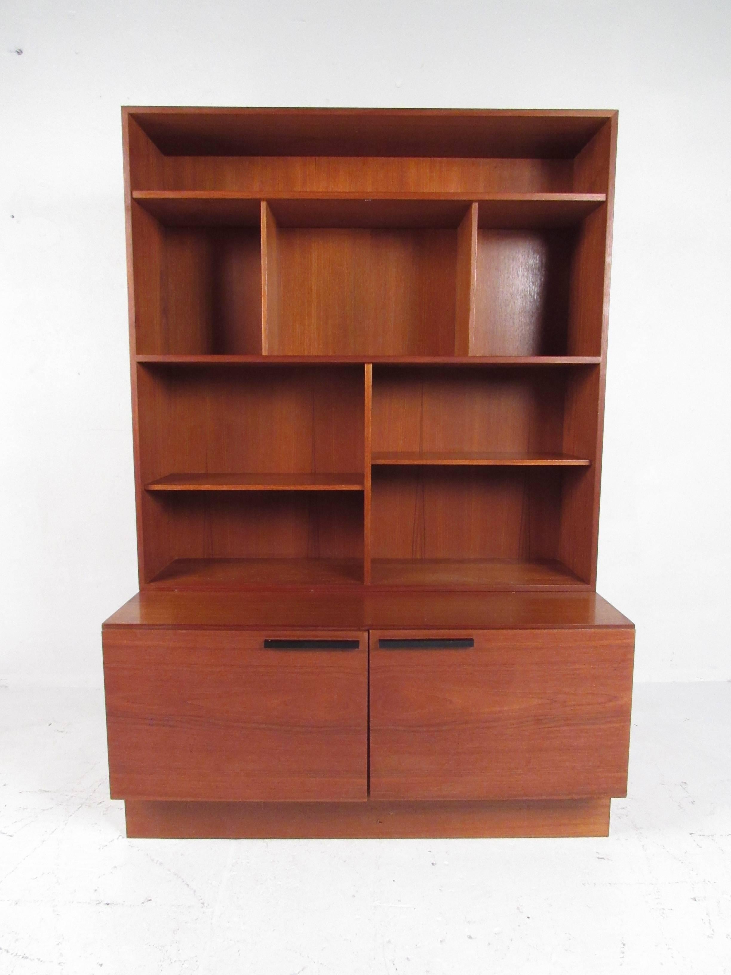 This Scandinavian Modern bookshelf by Ib-Kofod Larsen features spacious shelf storage and lower cabinets to provide adequate organization and display for home or office. Quality Mid-Century Modern Reolsystem wall unit design includes teak