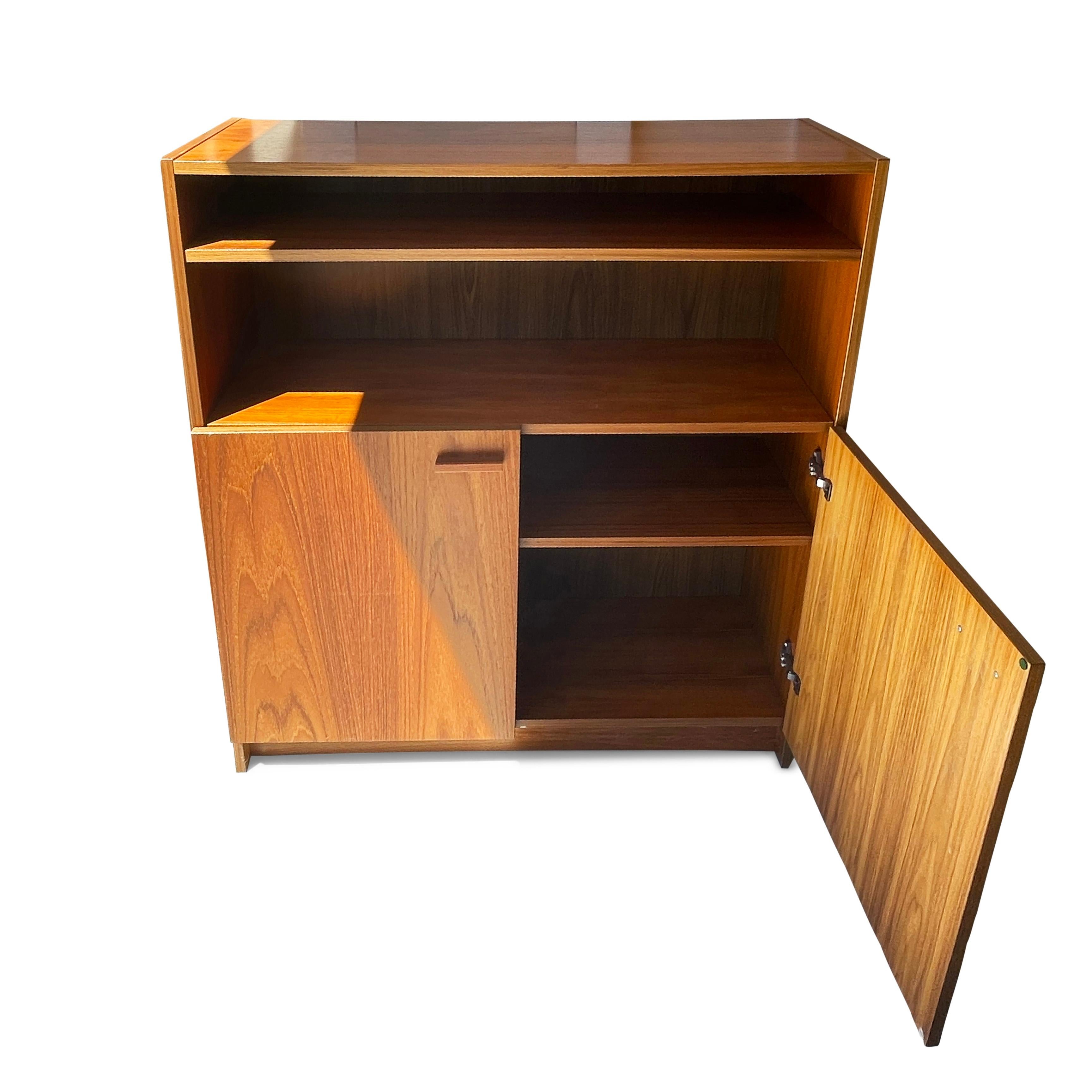 Ein wunderschönes, typisch skandinavisch-modernes Teakholz-Bücherregal mit vier Einlegeböden, von denen zwei zwischen reich gemaserten Türen verborgen sind. 

In gutem Vintage-Zustand mit leichten alters- und gebrauchsbedingten Gebrauchsspuren. 
