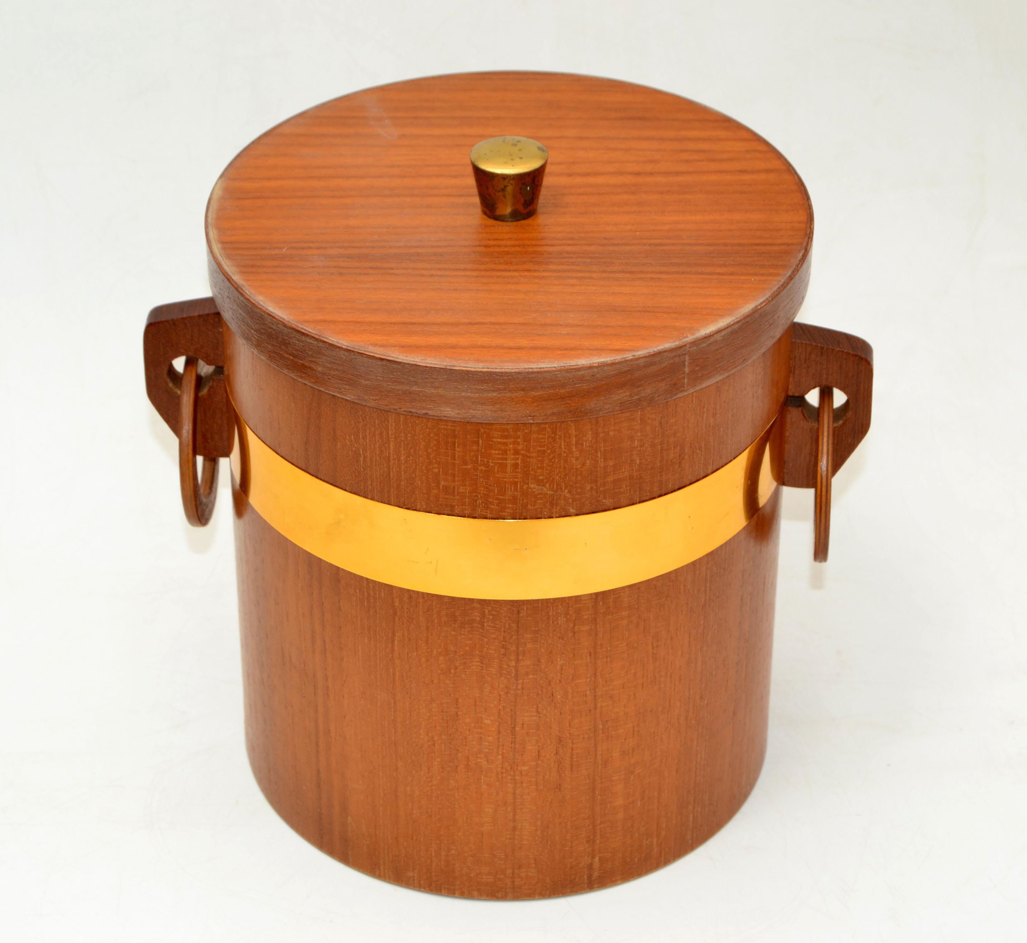 Danish modern two-tone teak lidded ice bucket with Brass Knob. 
The interior is lined with white plastic.
In good vintage condition. The Teak Wood has dried out over the many years and could use some teak oil. Brass Knob has patina.