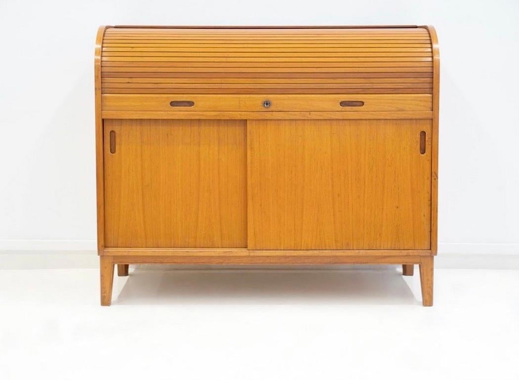 Scandinavian made cabinet veneered with teak. Top part with roll-up flap, bottom with two sliding doors, behind which are storage compartments with a shelf. Key included.

