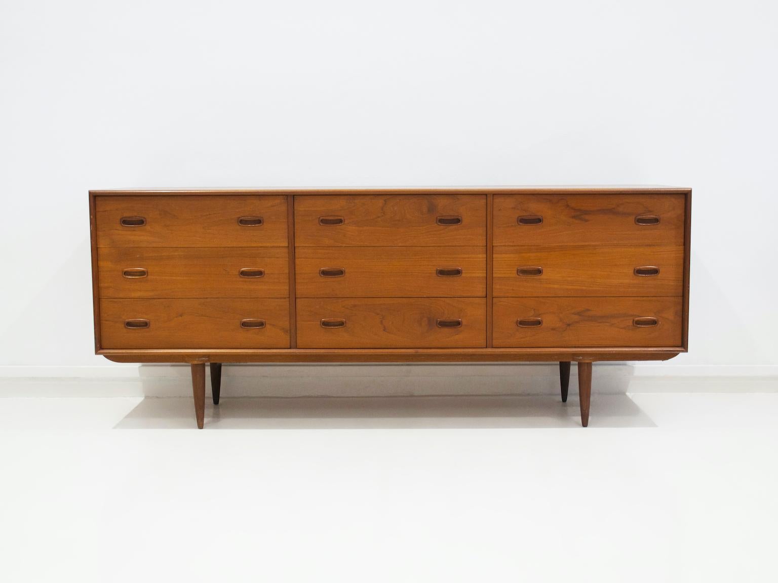 Scandinavian style teak sideboard with nine drawers from the 1960's. Tapered legs and built-in pulls on the drawers.