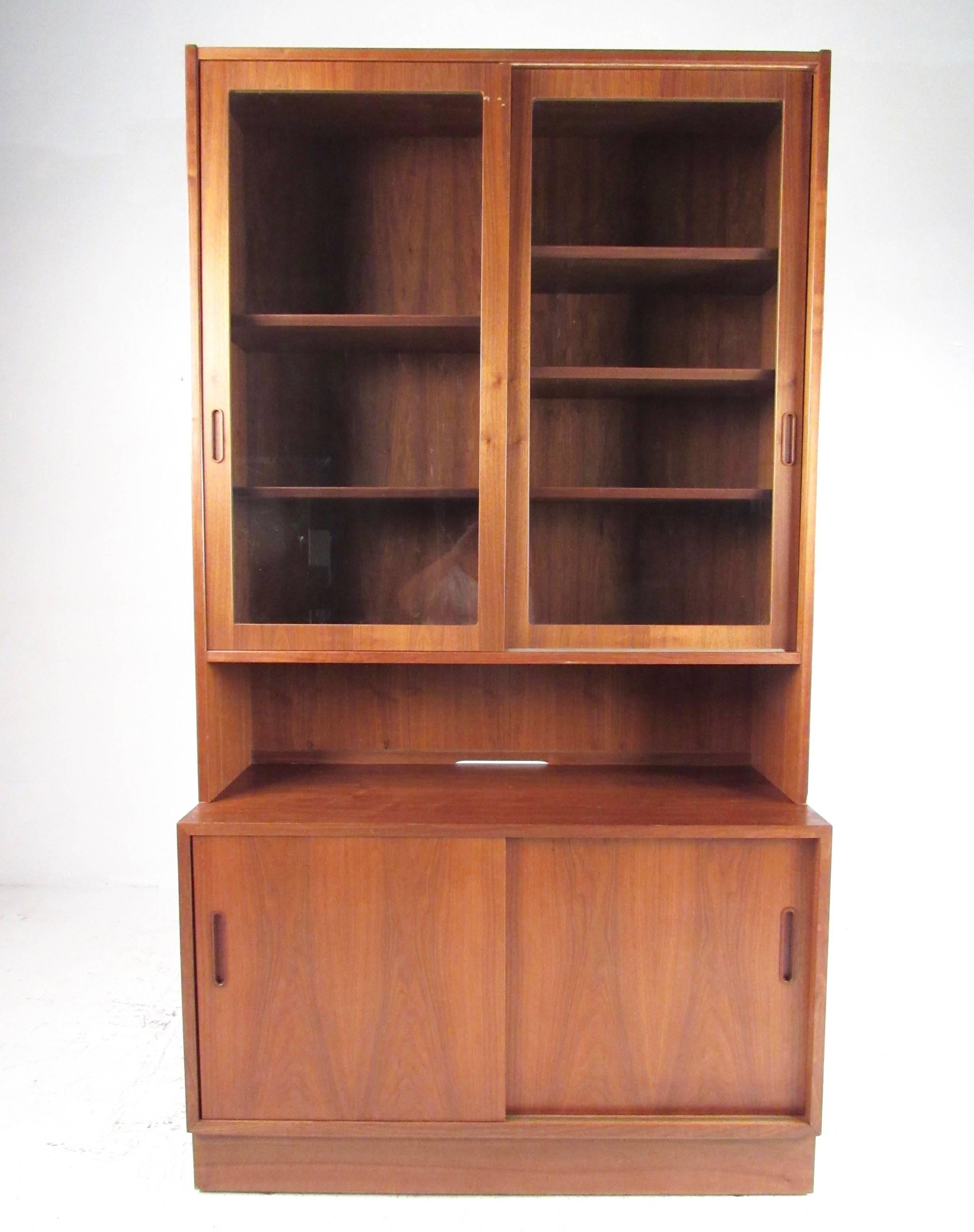 This stylish Scandinavian teak cabinet with display hutch is perfectly suited for kitchen or dining room storage, offering ample storage space in a tight footprint. Lower cabinet sliding doors reveal adjustable shelves, while carved Danish handles