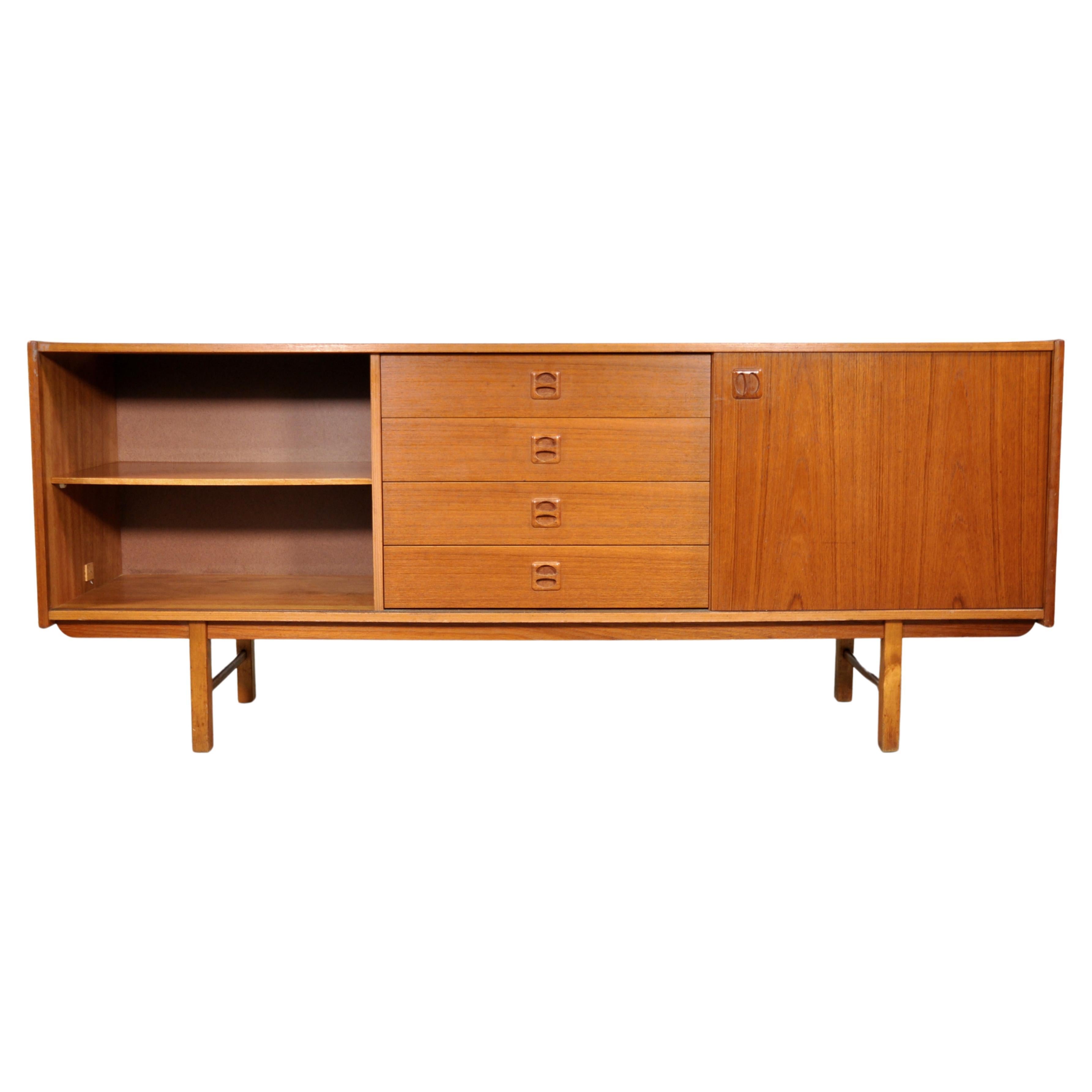 Vintage Swedish Modern teak bar cabinet dating from the 1960s. The sideboard features a central column with four drawers with sculpted teak pulls, flanked by a sliding door (originally two doors) opening to a cabinet space fitted with a shelf that