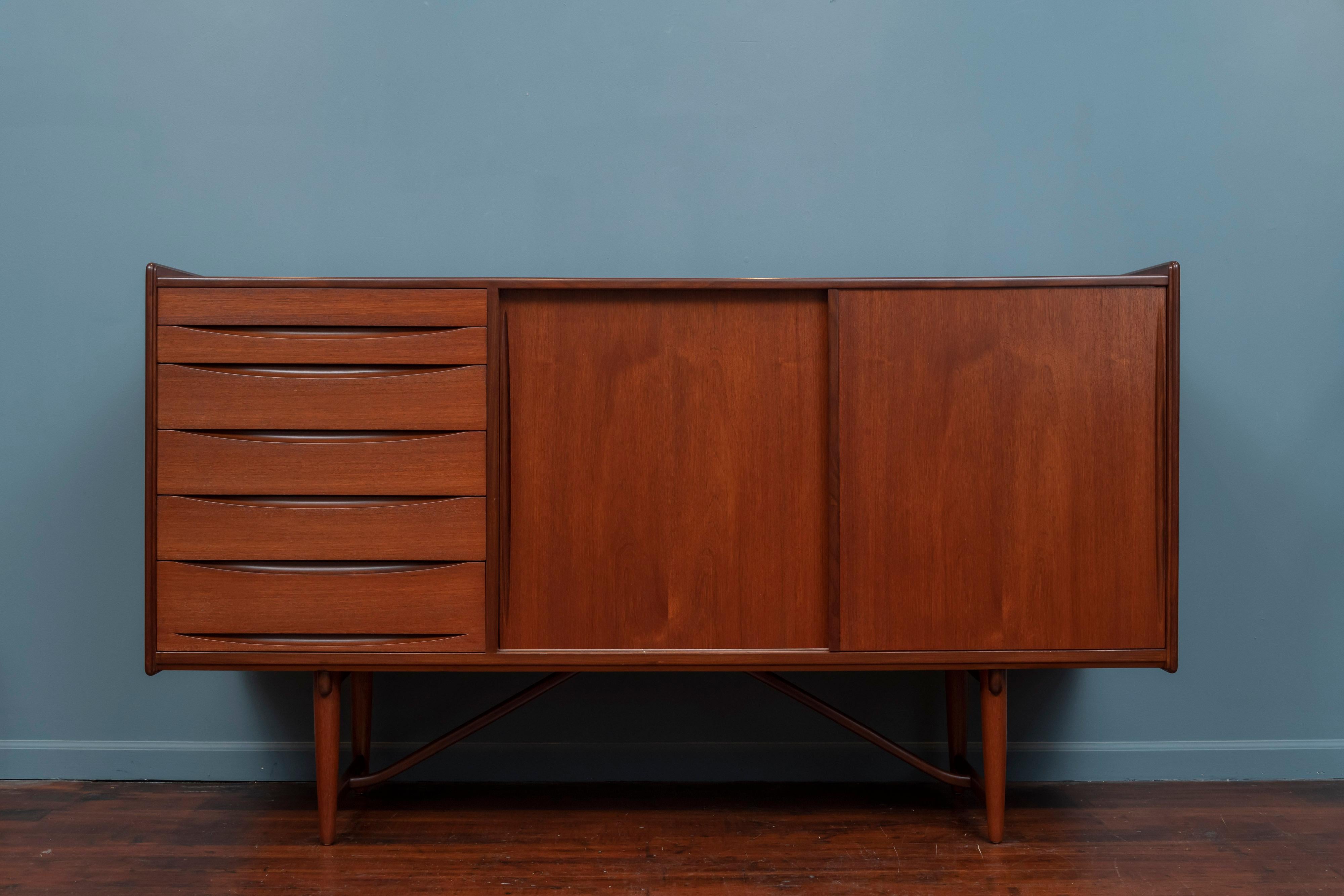 Scandinavian Modern teak credenza made with high attention to detail and construction, newly refinished. 
Architectural base/leg construction with sculpted 6 eyelid design drawers next to a large storage area with two adjustable shelves. A great