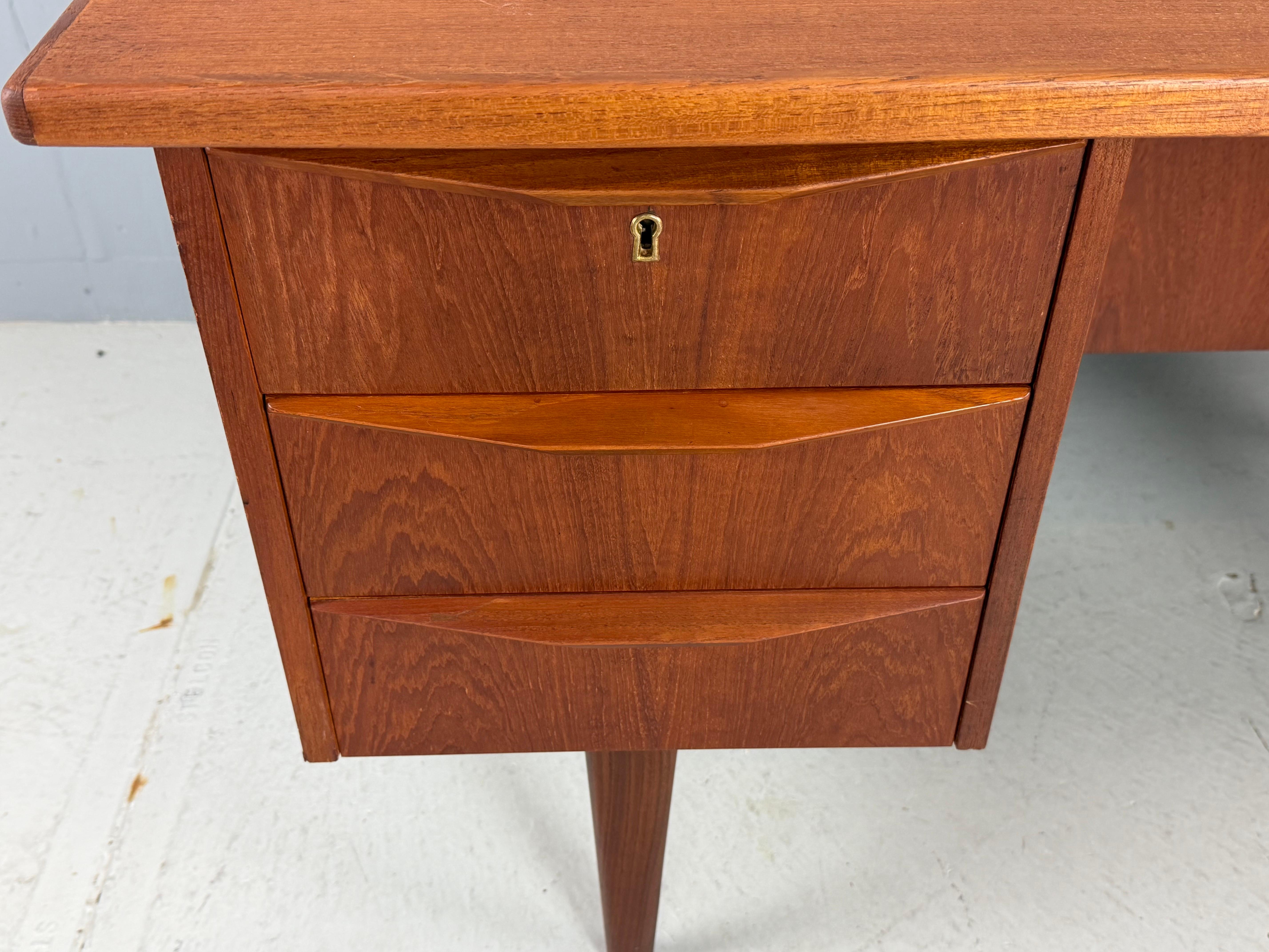 Scrivania d'epoca moderna scandinava realizzata negli anni '60 in Danimarca 
La scrivania è realizzata in legno di teak ed è in buone condizioni vintage con una bella patina di legno. La scrivania è composta da 6 cassetti frontali, due dei quali