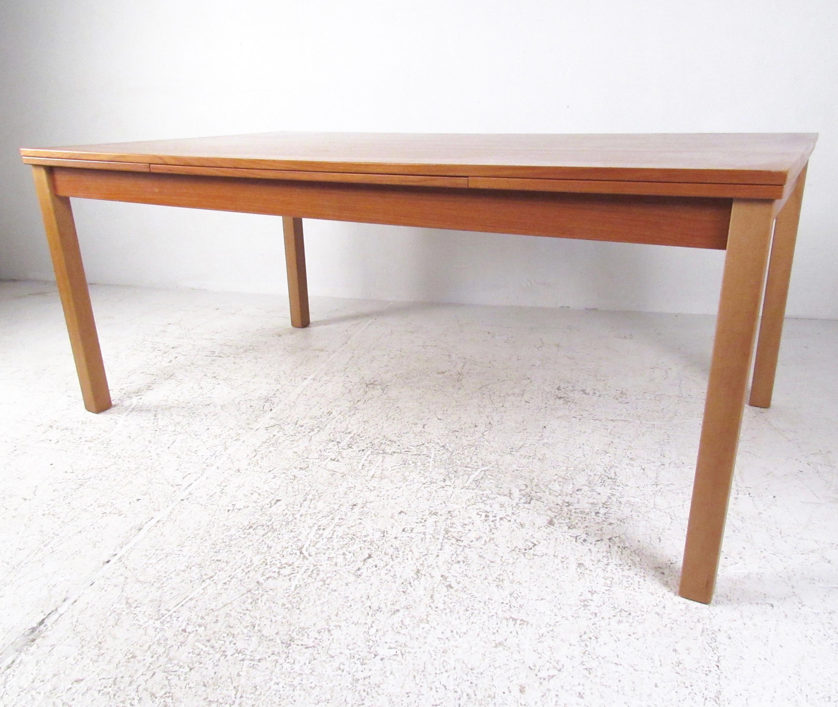 This stylish Danish modern dining table by Ansager Møbler A/S of Denmark makes for a unique addition to any interior dining area. Rich teak finish and easy draw leaf extensions make this an impressive table perfect for entertaining in any situation.