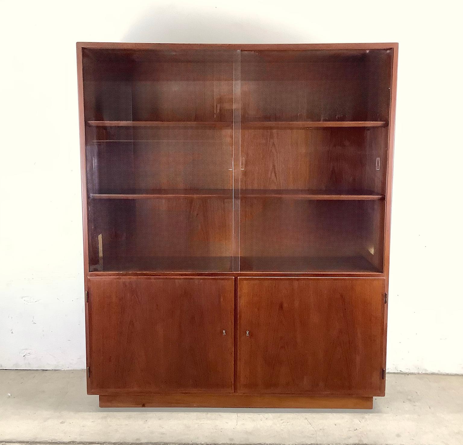 This Mid-Century Glass-Front Teak Display Cabinet Bookcase is a remarkable vintage piece that effortlessly combines style and functionality. This Scandinavian Modern teak cabinet is a timeless vintage treasure that will elevate any interior with its