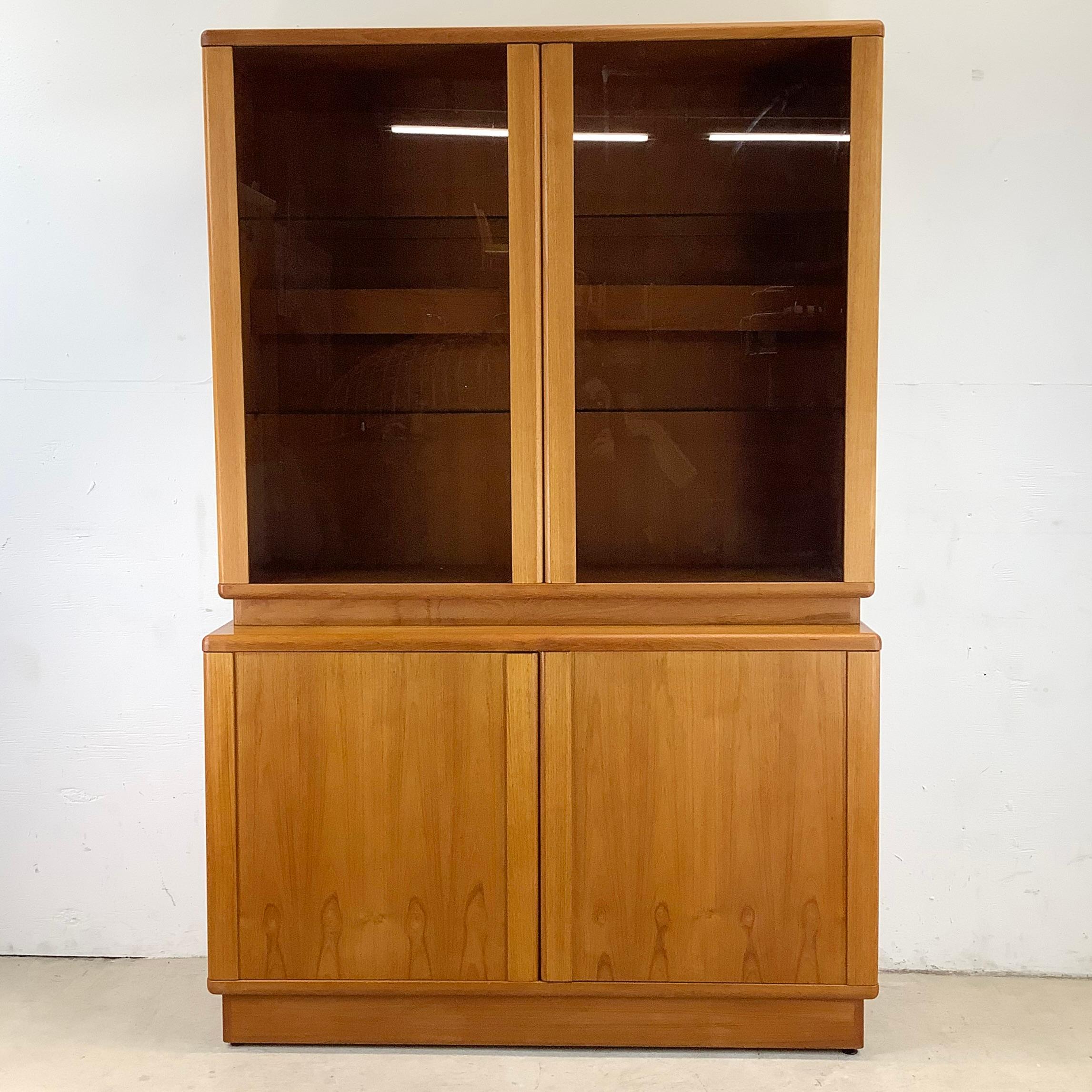 Enhance your home decor with this exquisite late 20th-century vintage two-piece teak display cabinet and hutch. This stunning Scandinavian Modern style piece showcases the timeless elegance of teak wood, known for its warm tones and rich grain