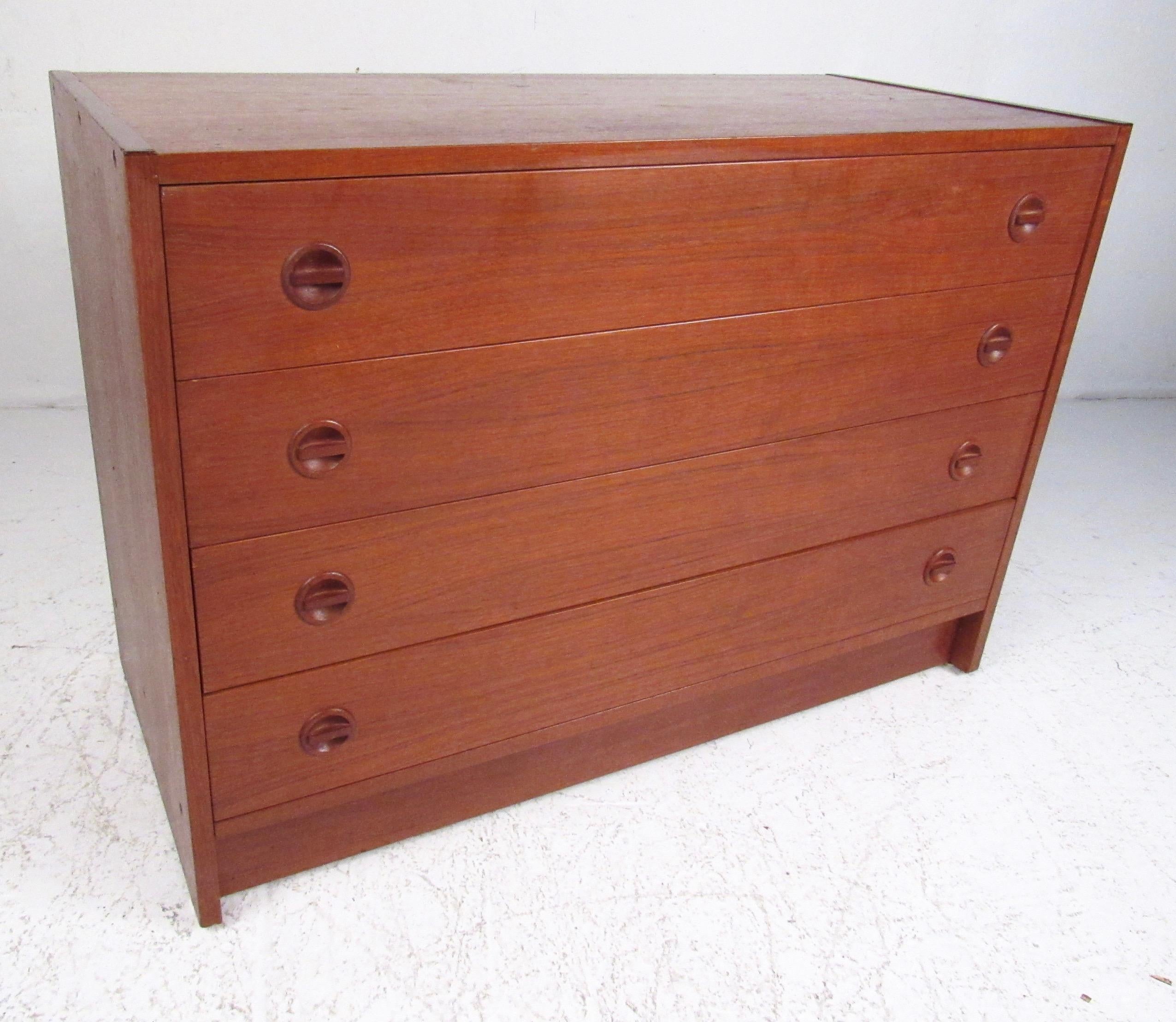 This vintage modern four-drawer dresser features rich Scandinavian teak finish complete with carved wood pulls. Spacious chest of drawers perfect for bedroom storage. Mid-Century Modern charm and Danish manufacturing make this ideal for home or